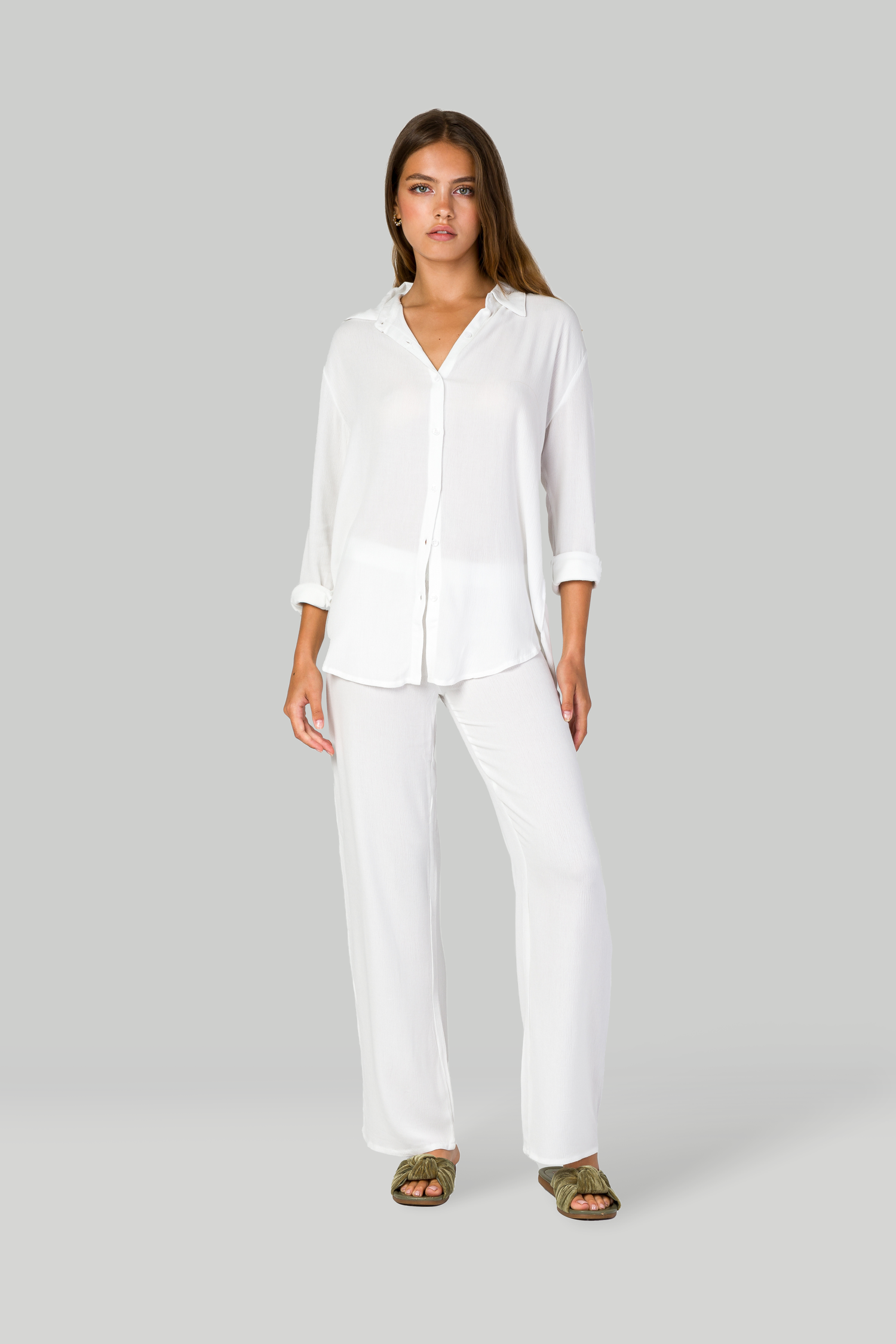 Casual white outfit featuring collared shirt and straight-leg pants paired with slide sandals.