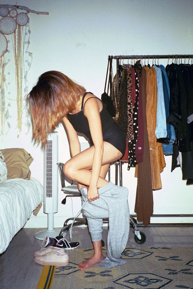 Series of photos showing someone getting dressed in a bedroom with clothes hanging in background.