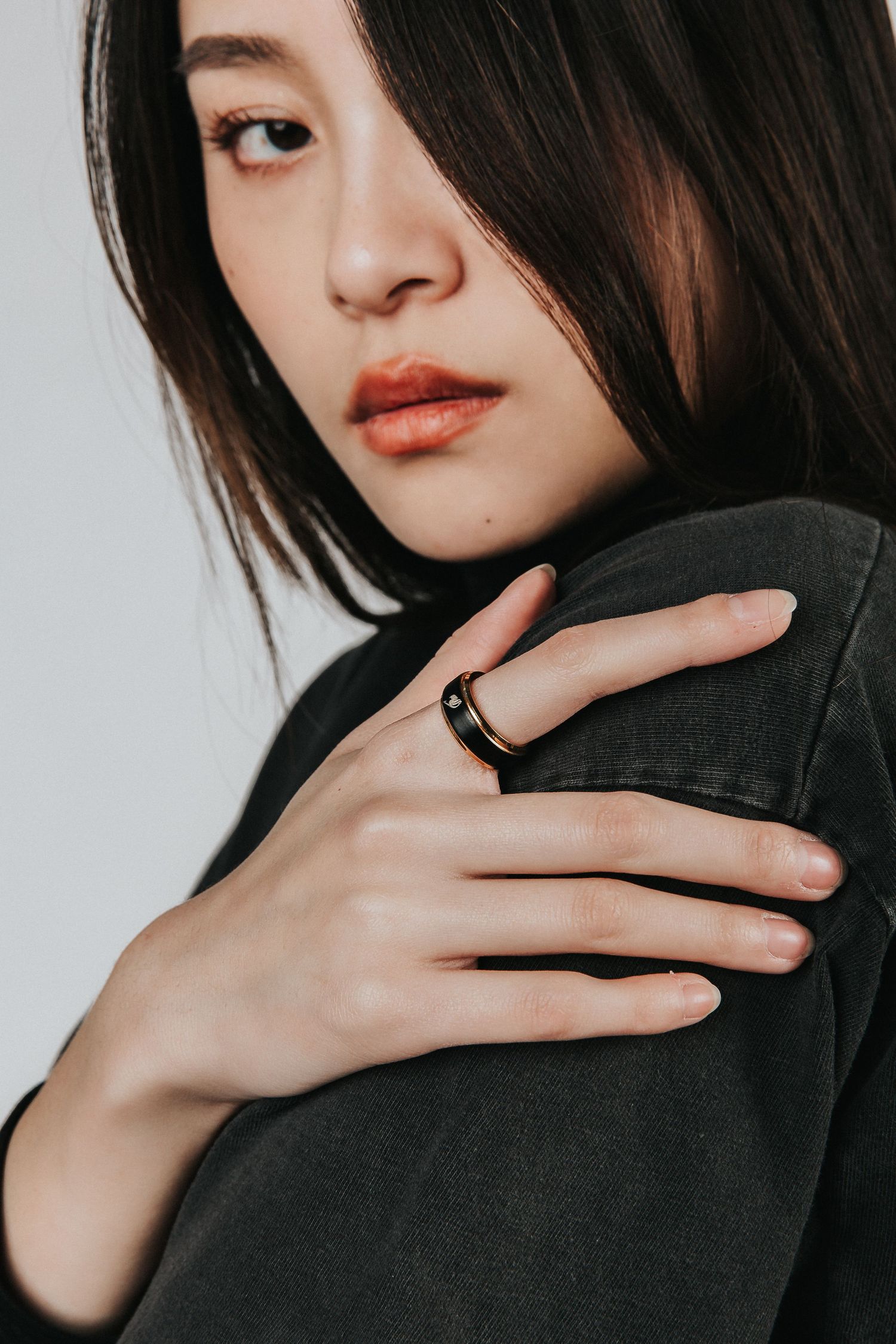 Fashion portrait showing model in black jacket with dramatic makeup and ring.