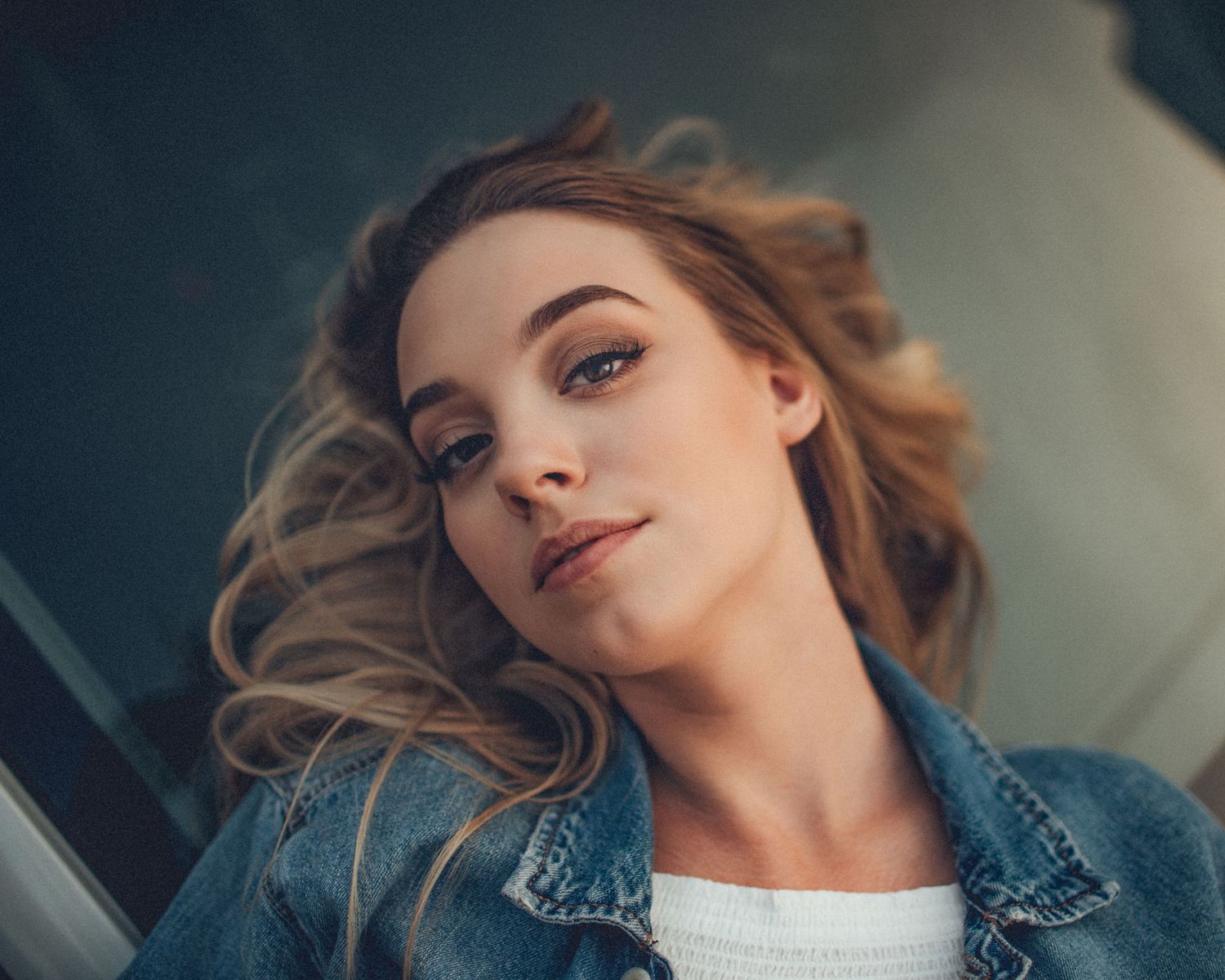 Relaxed pose in denim jacket showing confident expression.