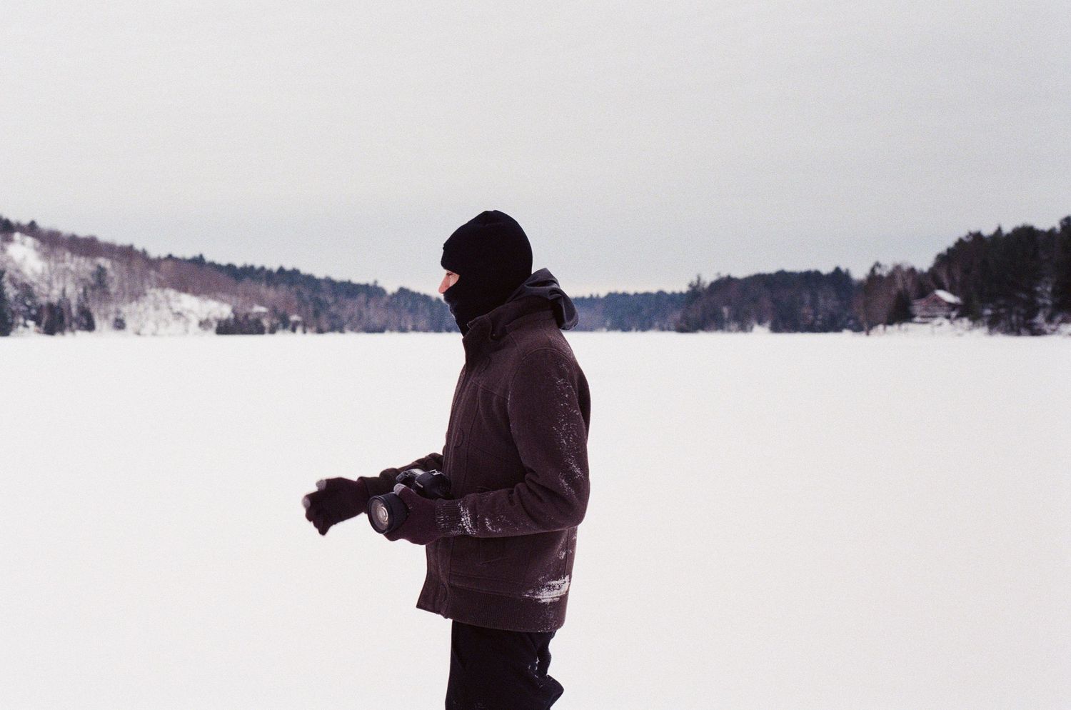 Silhouette of person photographing snowy winter landscape.