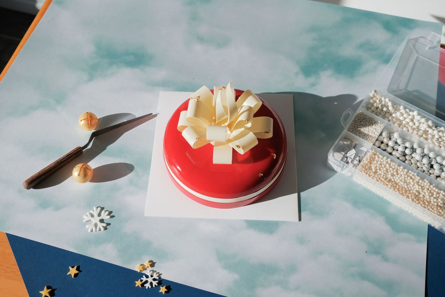 Decorative arrangement with red glazed dessert and white paper elements on blue background.