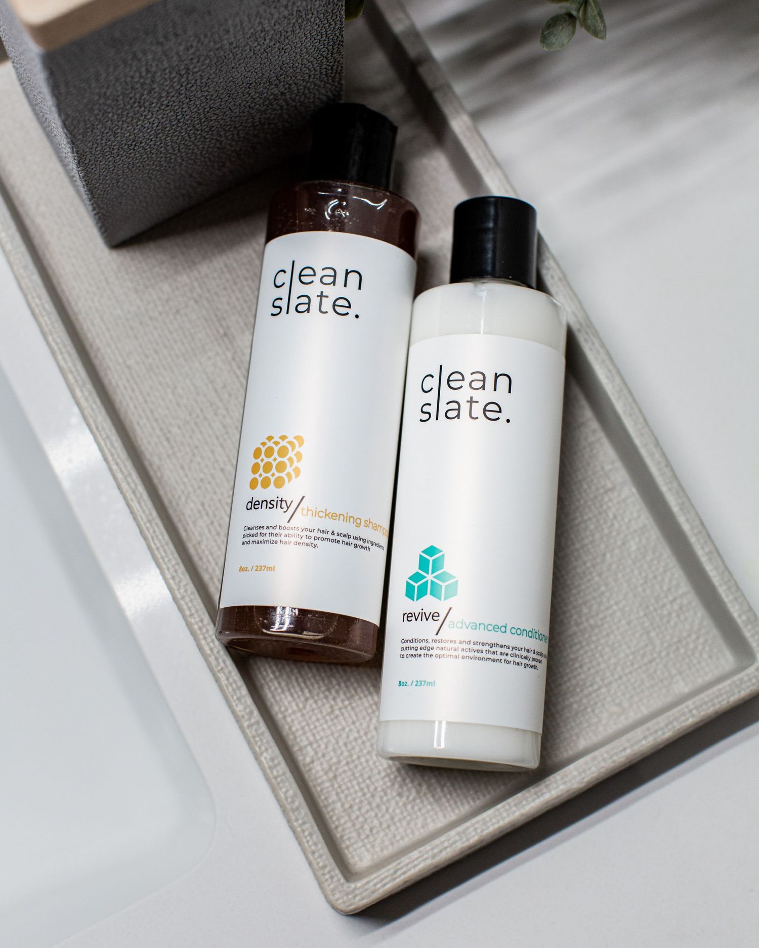 Two Clean Slate skincare bottles displayed on a light gray tray.