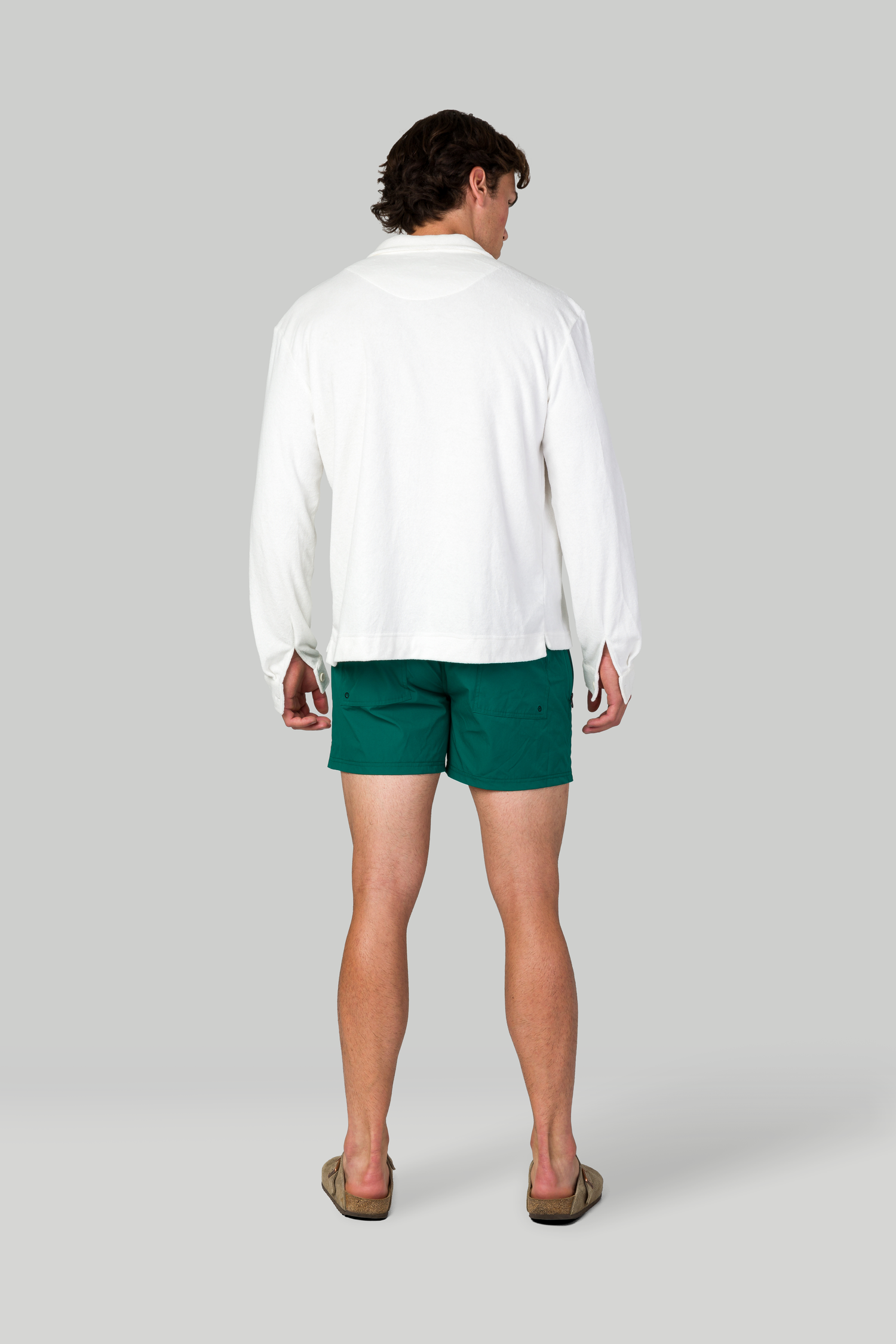 Back view of white shirt and emerald green shorts combination with casual shoes.