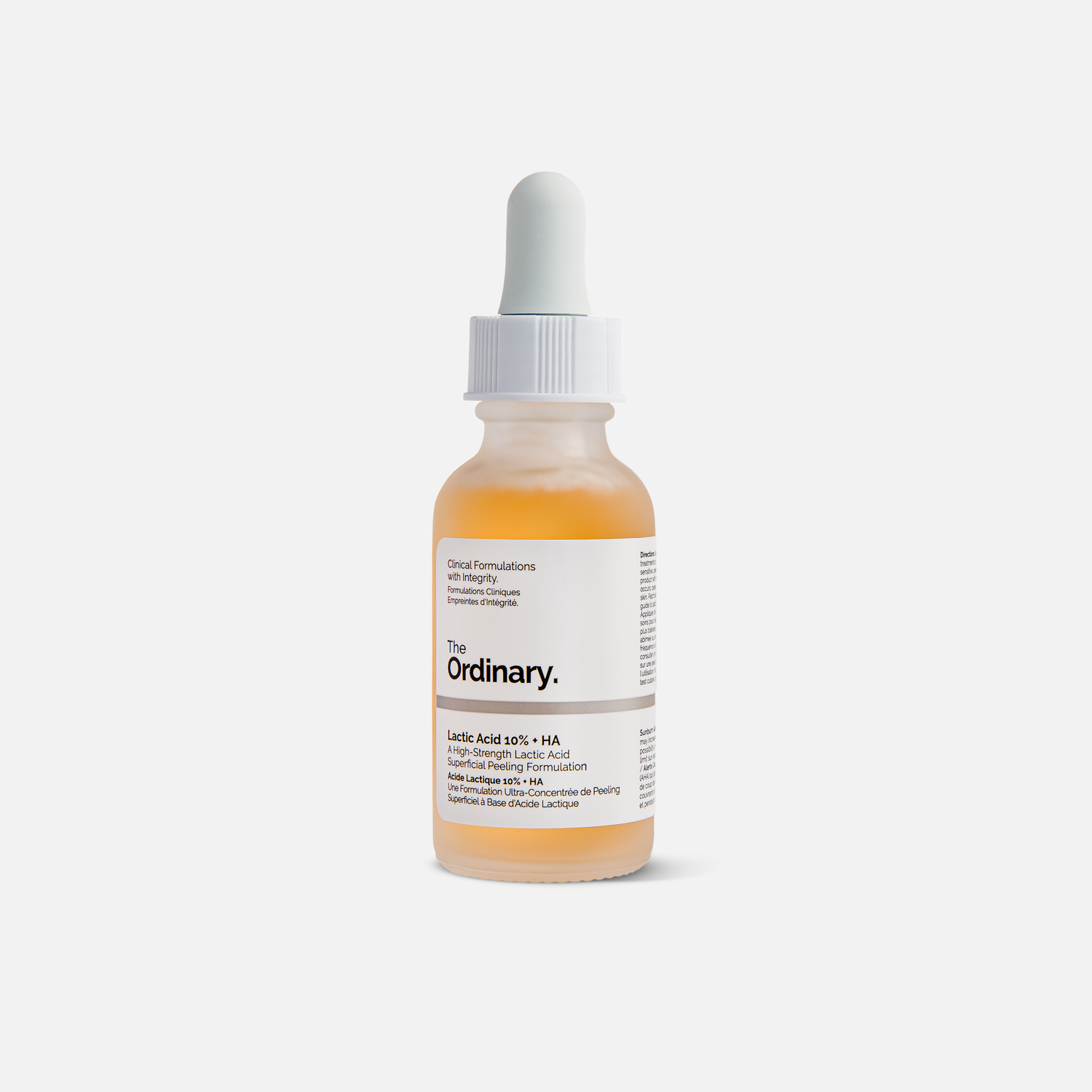 Clear glass bottle of The Ordinary skincare serum with orange liquid inside.