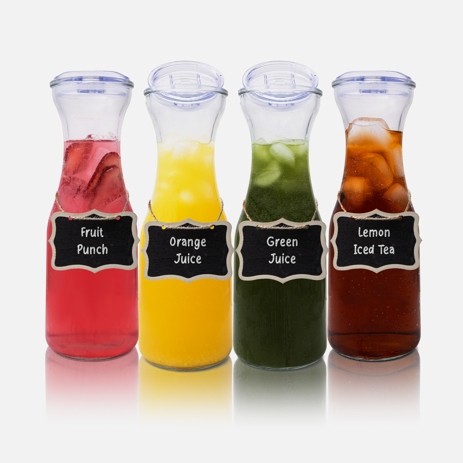 Four glass bottles filled with colorful fruit juices in red, yellow, green and brown shades.