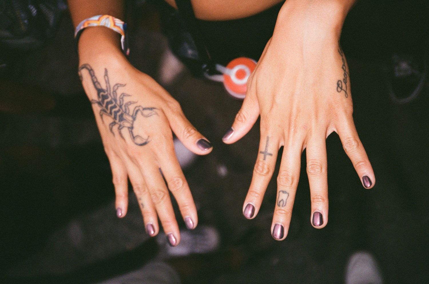 Multiple hands showing off dark painted fingernails against a black background.