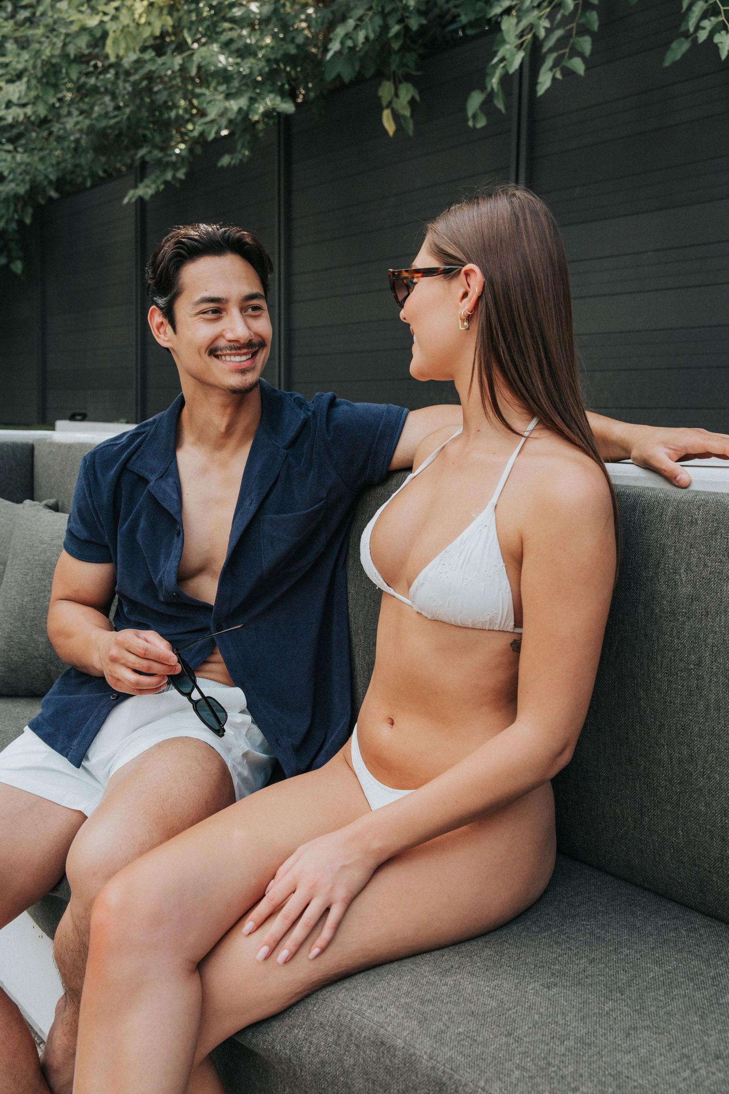 Couple in swimwear relaxing on concrete outdoor seating area.