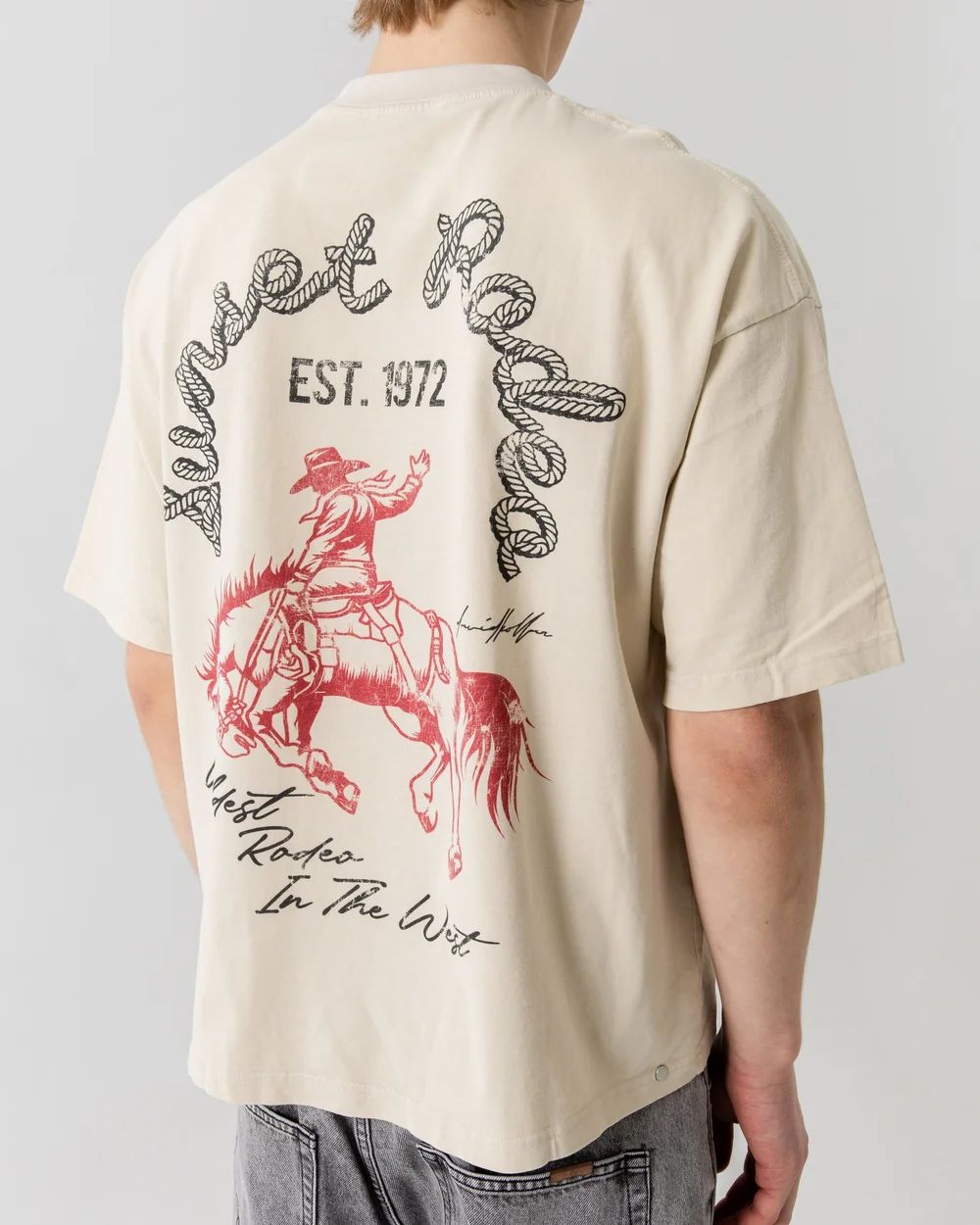 Cream colored t-shirt with vintage-style red graphic design featuring a jumping deer and text.