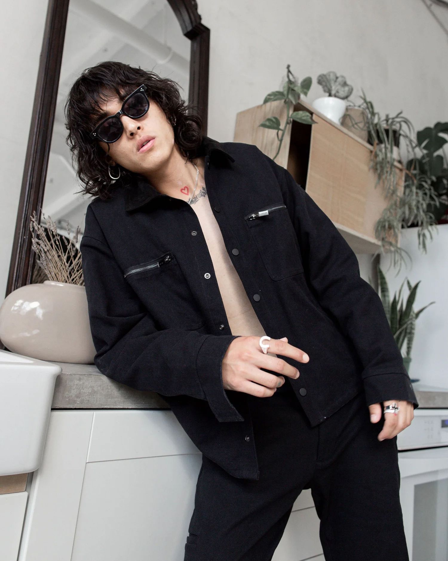 Fashion editorial with black outfit and sunglasses in modern interior setting.