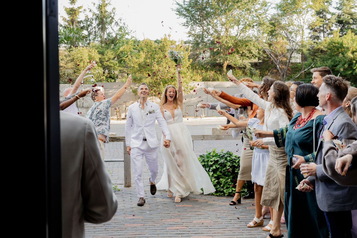 Wedding guests dance and celebrate together on an outdoor patio during a lively reception party.