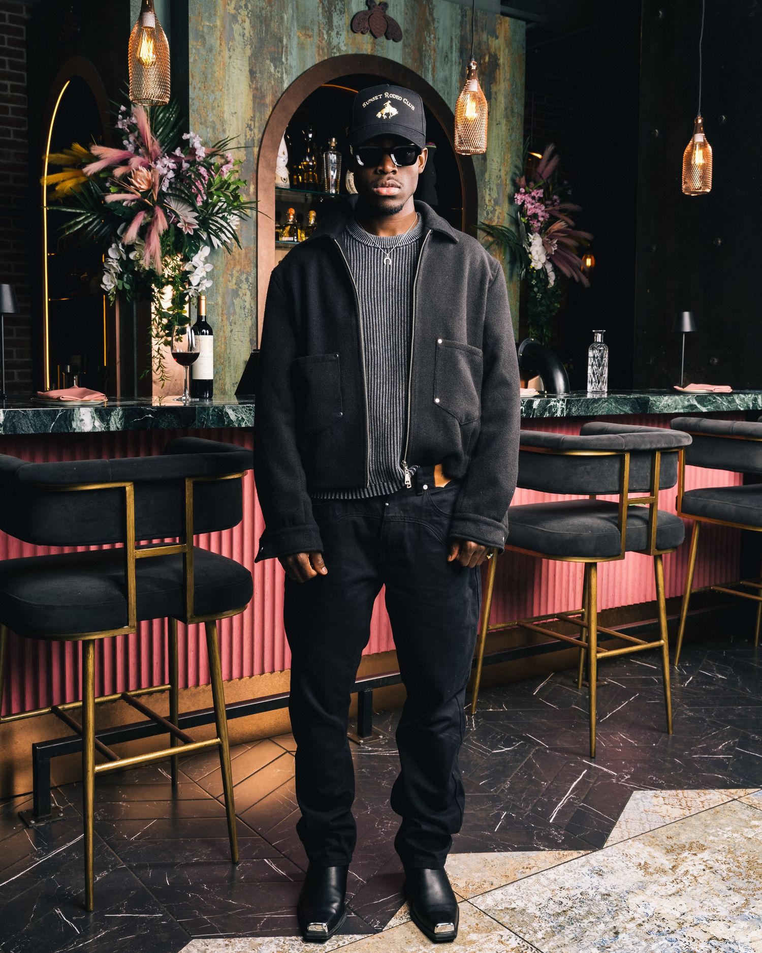 Full-length view of all-black outfit in restaurant setting.
