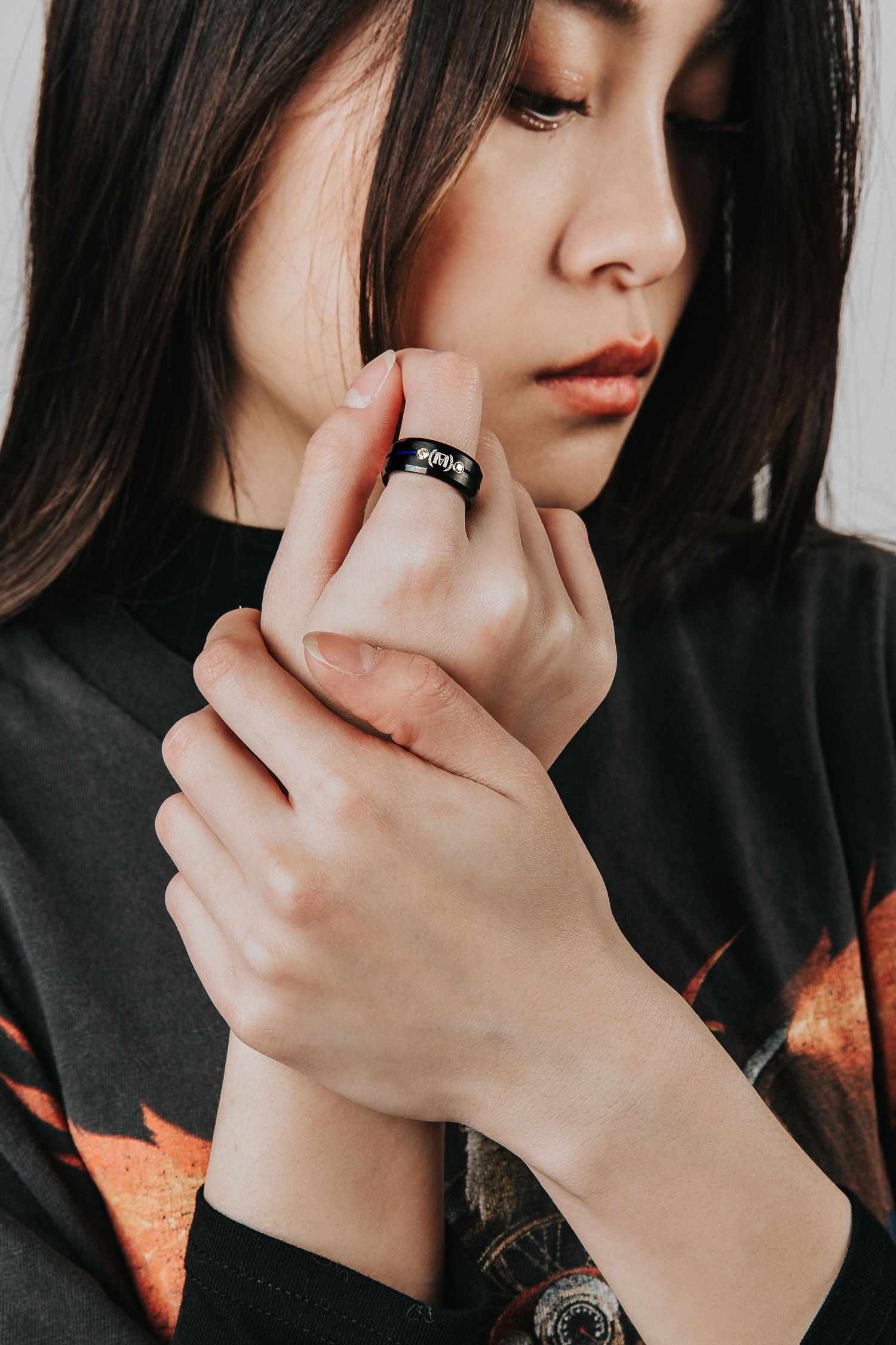 Close-up portrait showing hand with black ring against dark clothing.