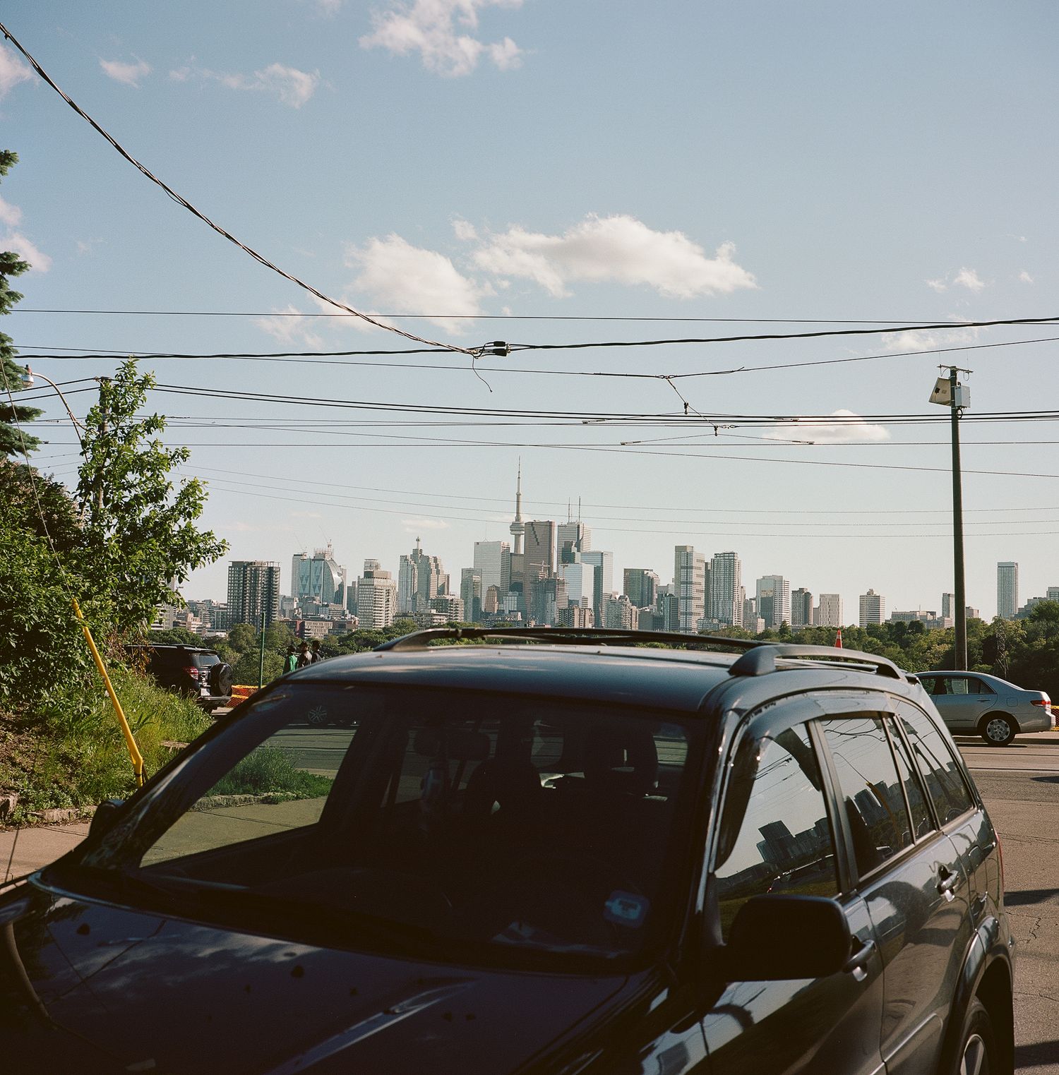 A black SUV parked on a street with Toronto's downtown skyline visible in the background.