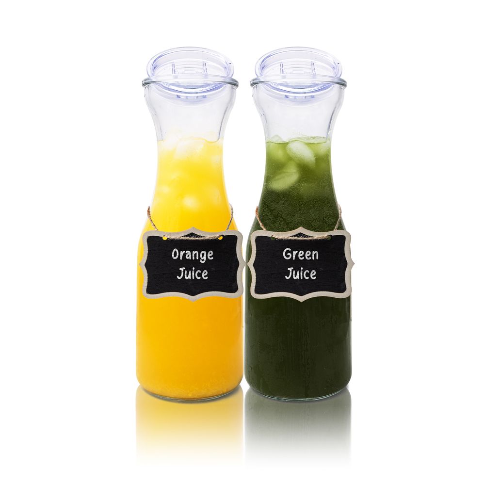 Glass carafes filled with bright orange and green juices labeled with chalkboard tags.