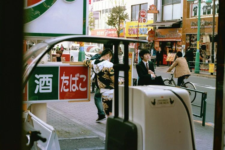 Row of storefronts and shops along a commercial street in Japan with signs and pedestrians.