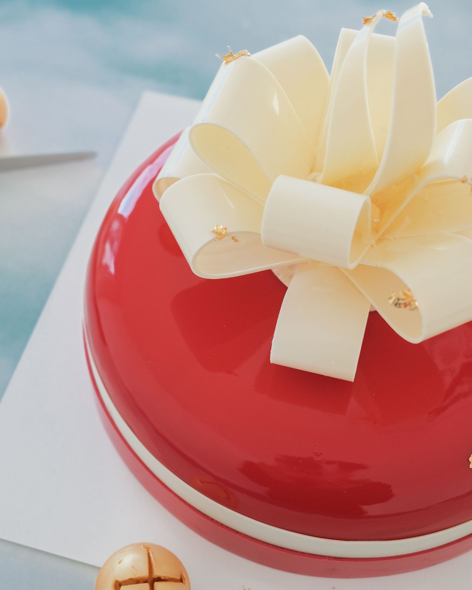 Close-up of a glossy red dessert decorated with white chocolate curls.