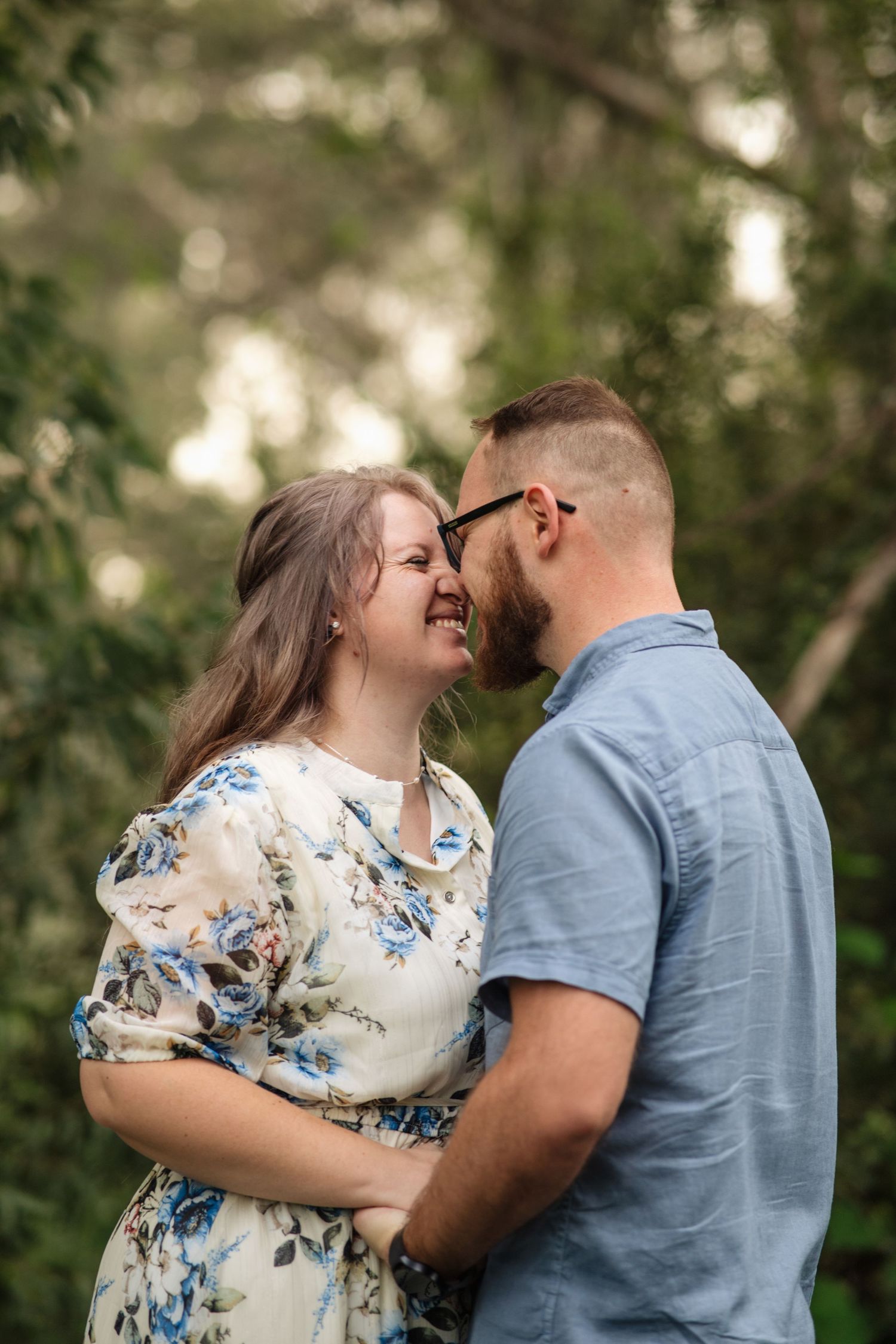 A couple on their engagement shoot in a forest, photo taken by Jordie Captures