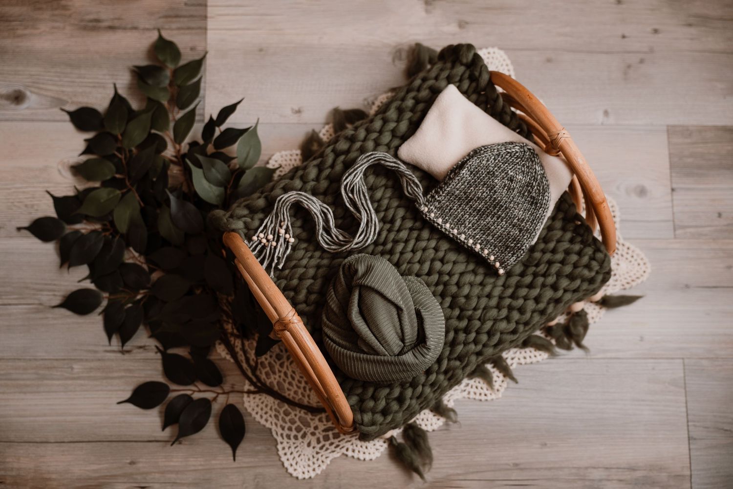 Wedding bouquet with dark green leaves and eucalyptus lies on rustic wooden floor next to brown leather shoes.