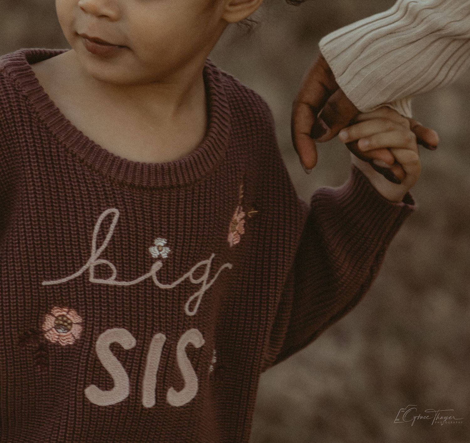 Child wearing a brown knit sweater embroidered with 