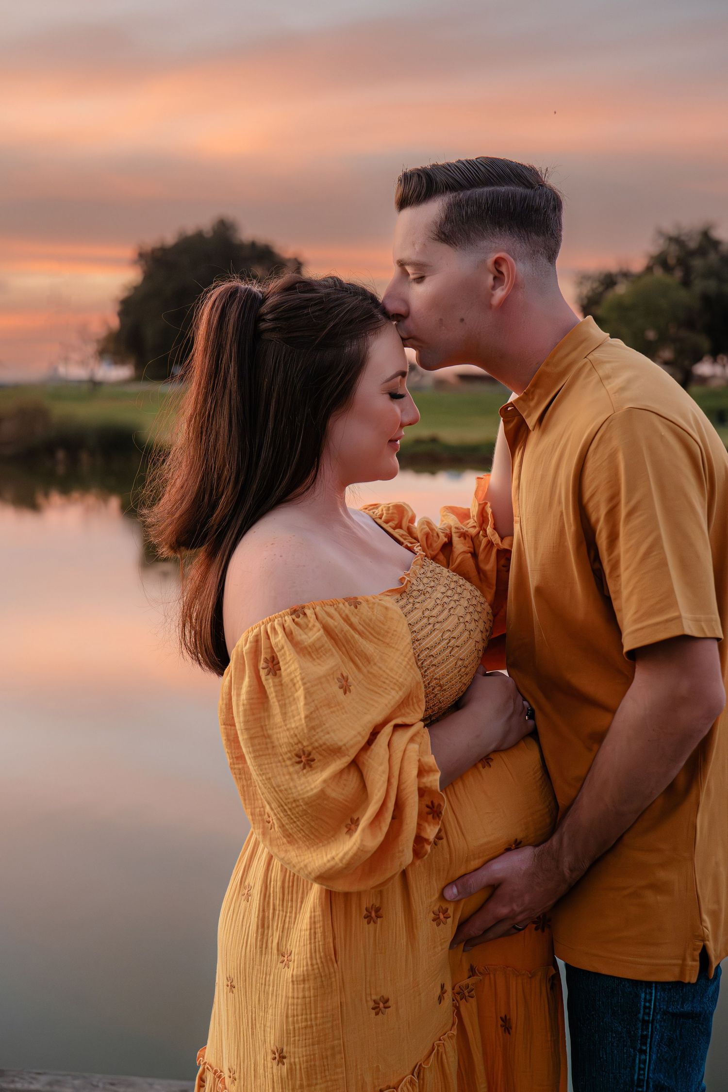 Couple in yellow outfits sharing an intimate moment by a lake during sunset in Roseville, CA