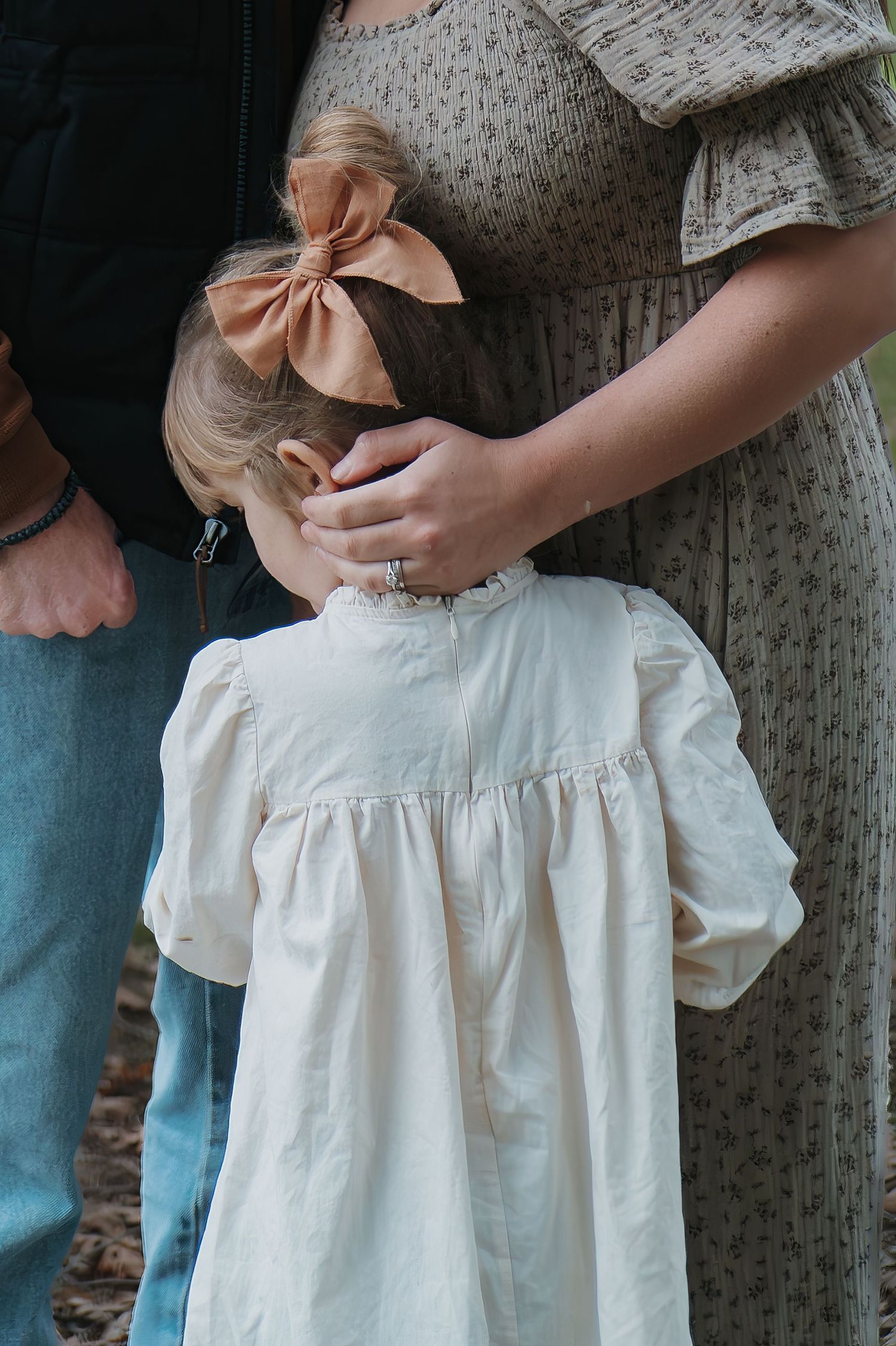 Detail shot of a white dress and pink bow being adjusted outdoors in Roseville, CA