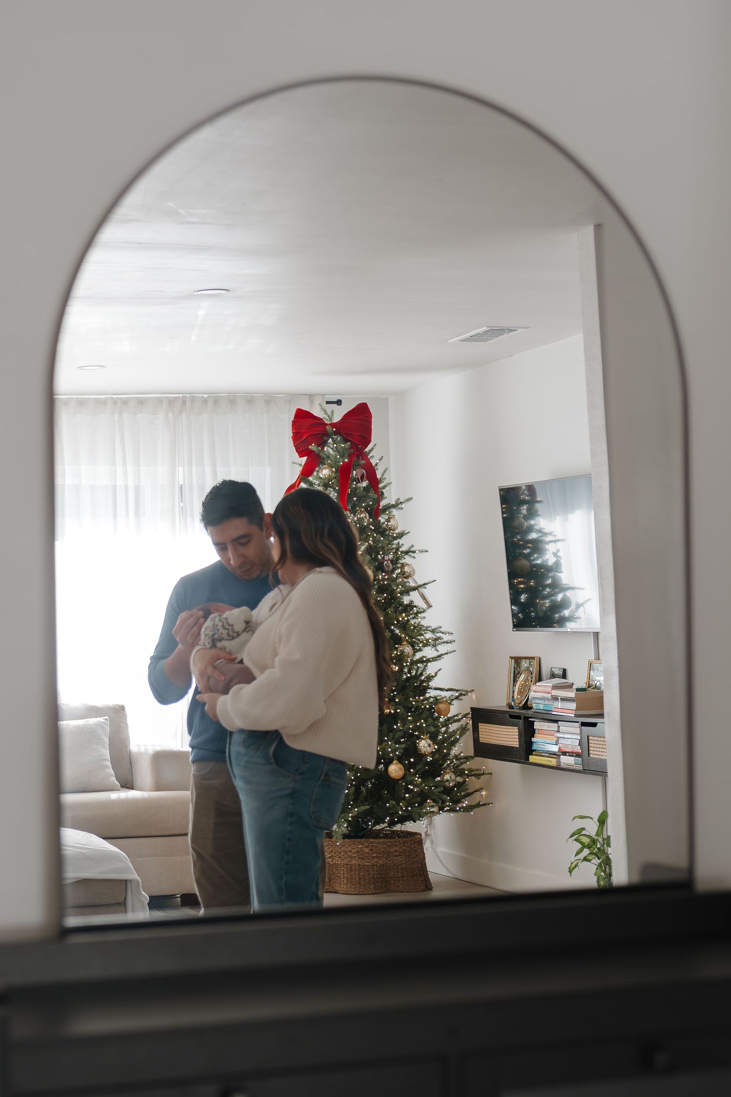 A series of four mirror reflections showing a romantic holiday moment in a cozy living room with a Christmas tree.