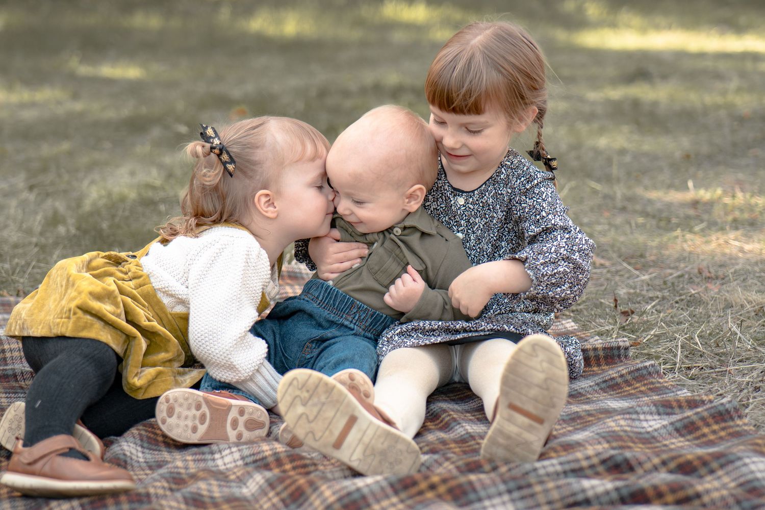 Family lying together on plaid blanket during autumn photoshoot in Roseville, CA