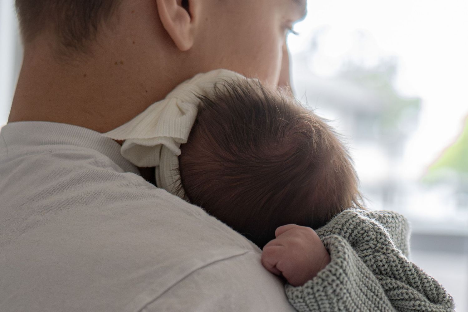 Intimate moment between couple holding their newborn baby in a bright indoor setting.