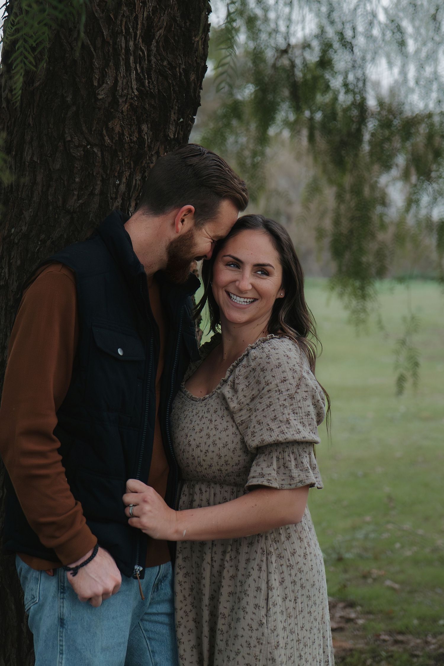 A joyful outdoor portrait against a tree with natural greenery in the background in Roseville, CA
