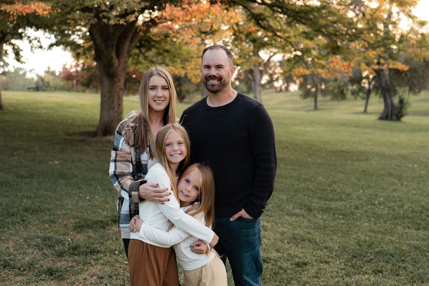 Candid family moment captured during golden hour in a grassy field with autumn colors in Roseville, CA