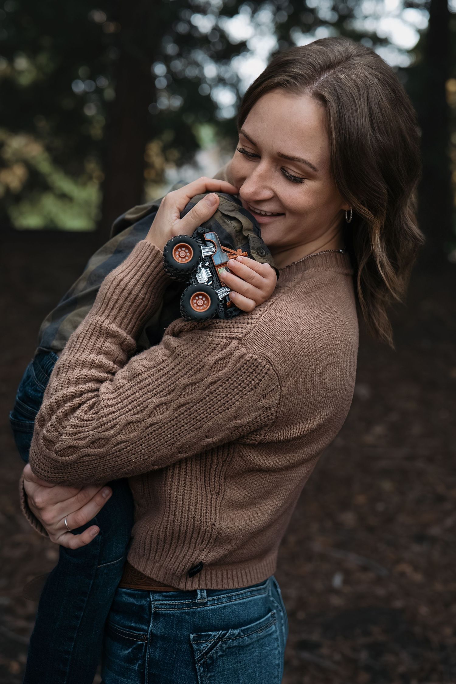 A tender moment captured in a brown sweater while holding a small toy car in Roseville, CA