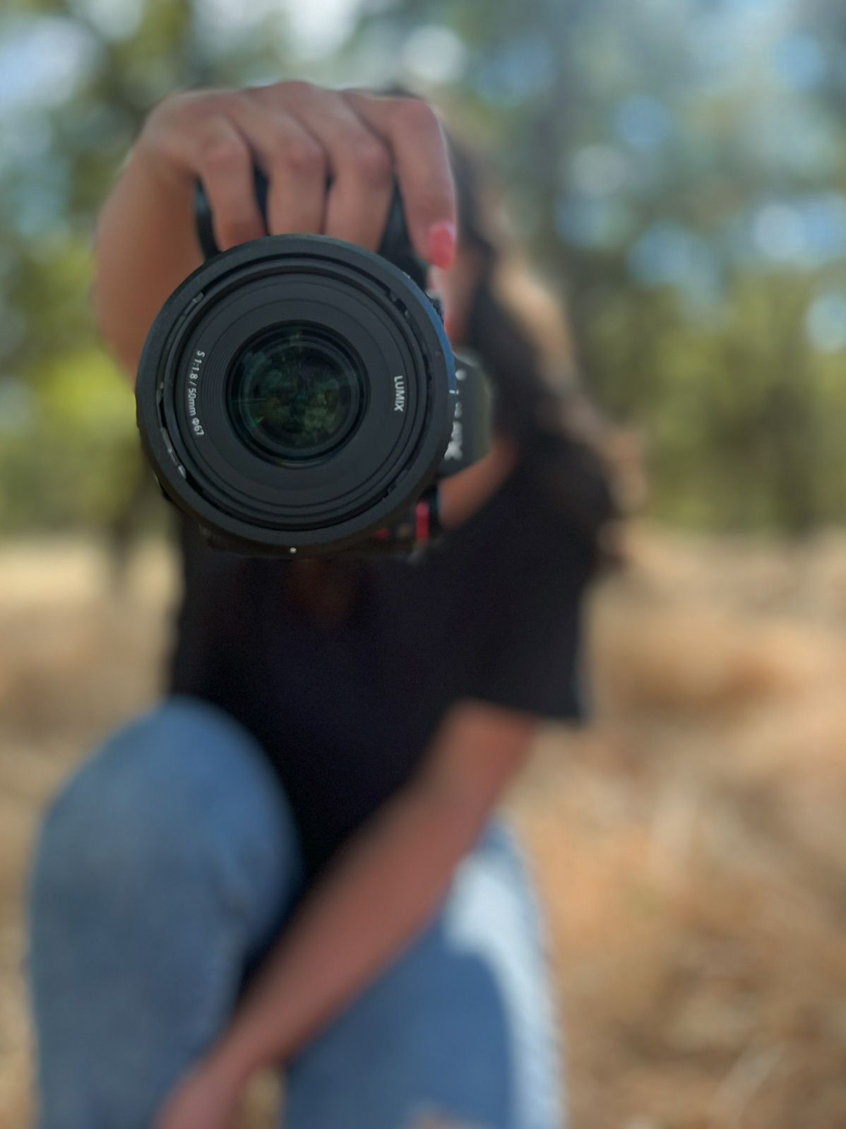 Close-up sequence of a camera lens being adjusted against a blurred outdoor background.