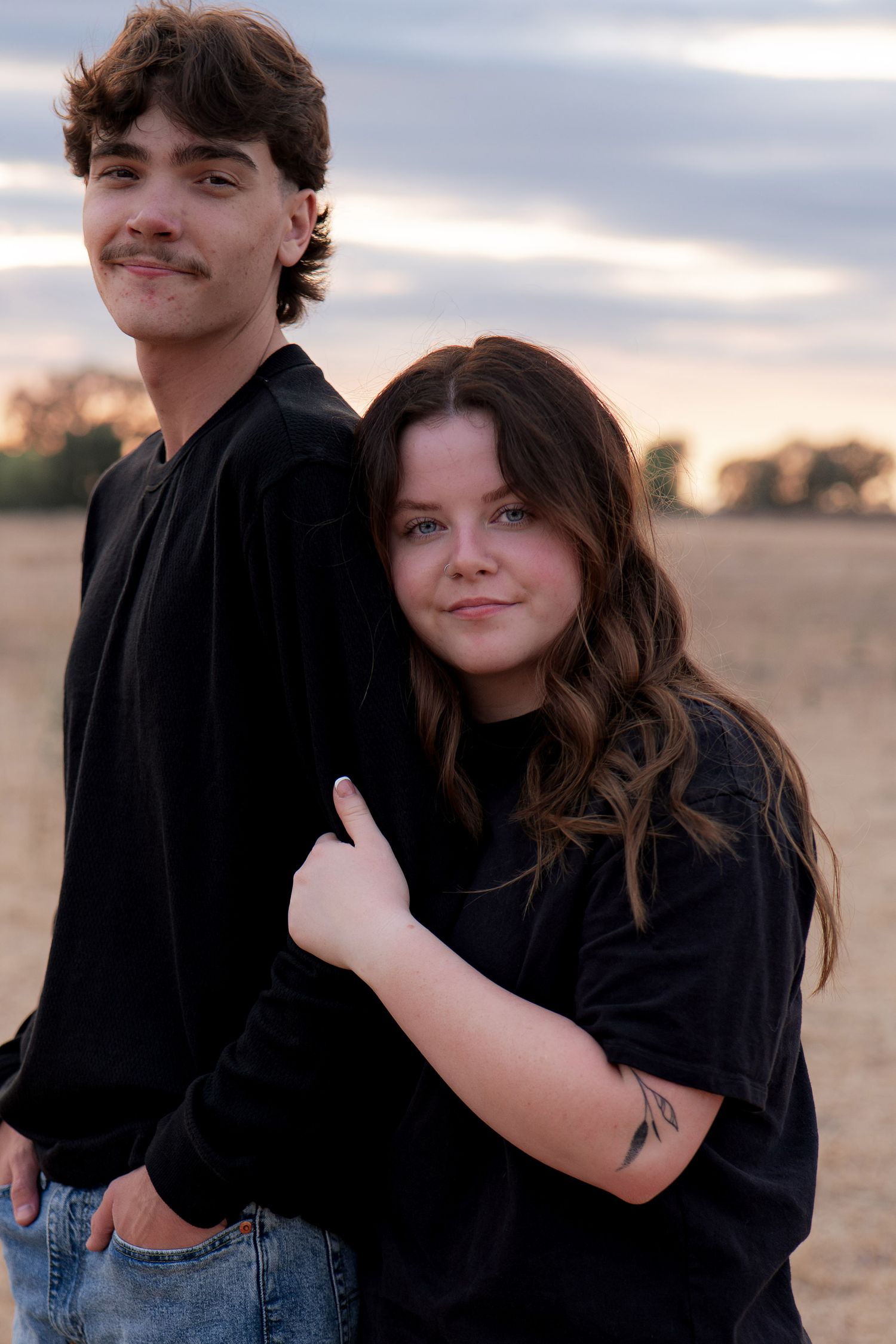 Couple in matching black shirts sharing playful moments in an outdoor setting in Roseville, CA