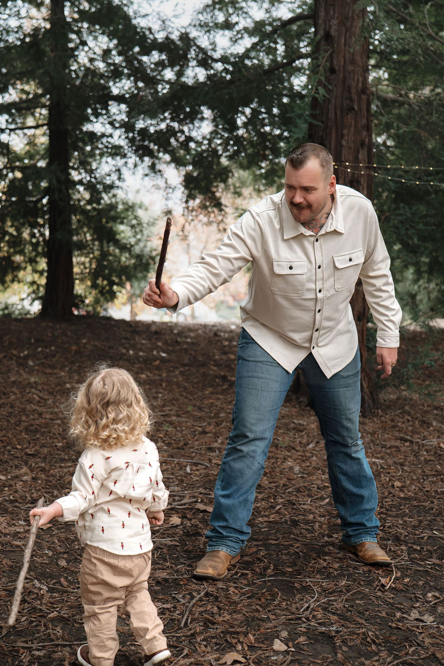 A playful outdoor scene in a wooded area with sticks being held while exploring nature together in Roseville, CA