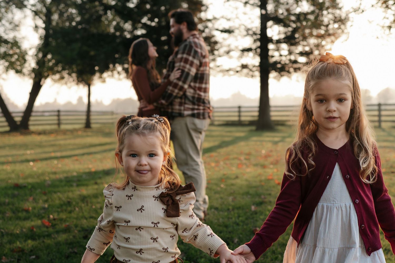 A family enjoys a warm autumn sunset in a grassy field wearing coordinated burgundy and white outfits in Roseville, CA