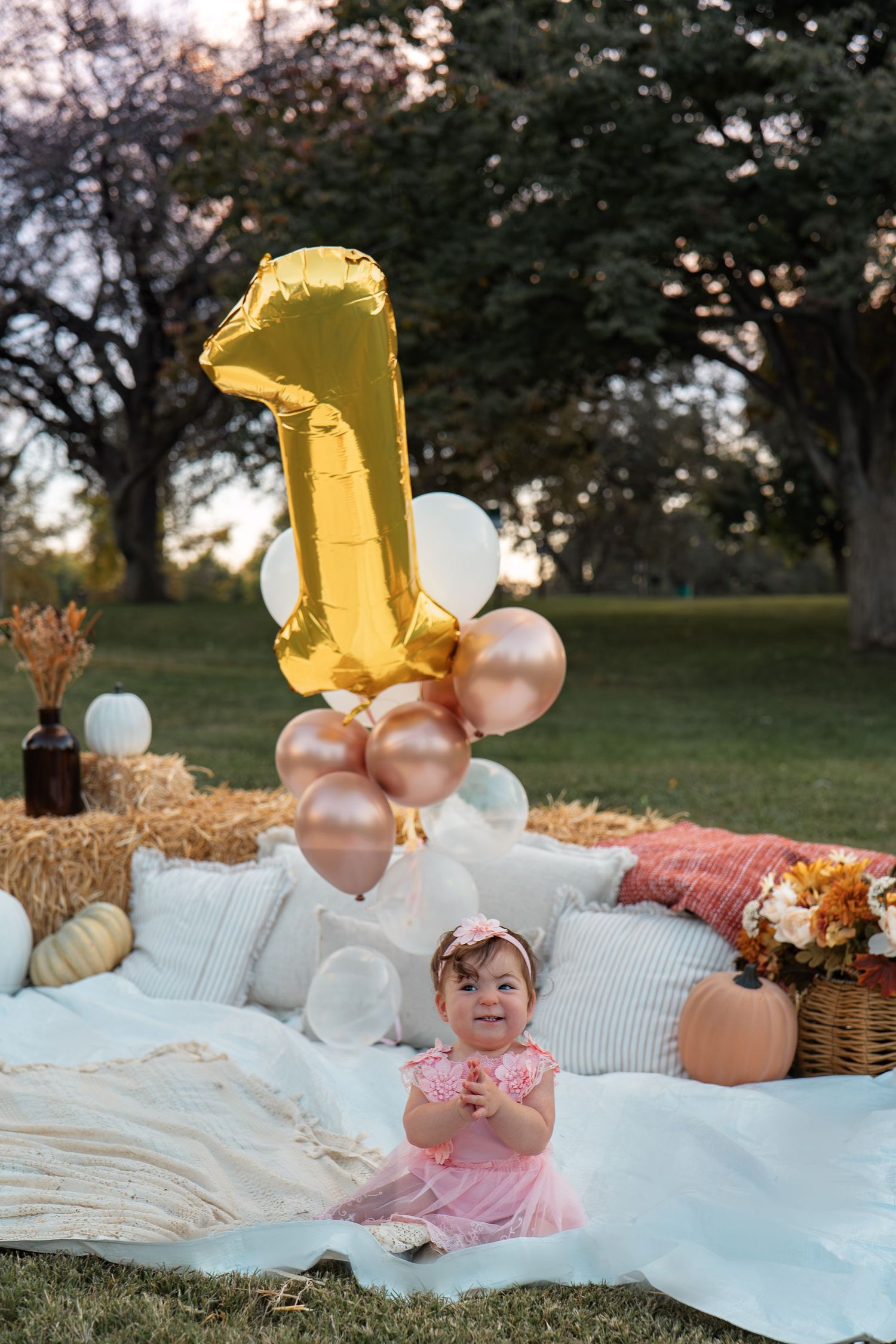 Outdoor first birthday setup with balloons, white blankets and autumn decorations in Roseville, CA