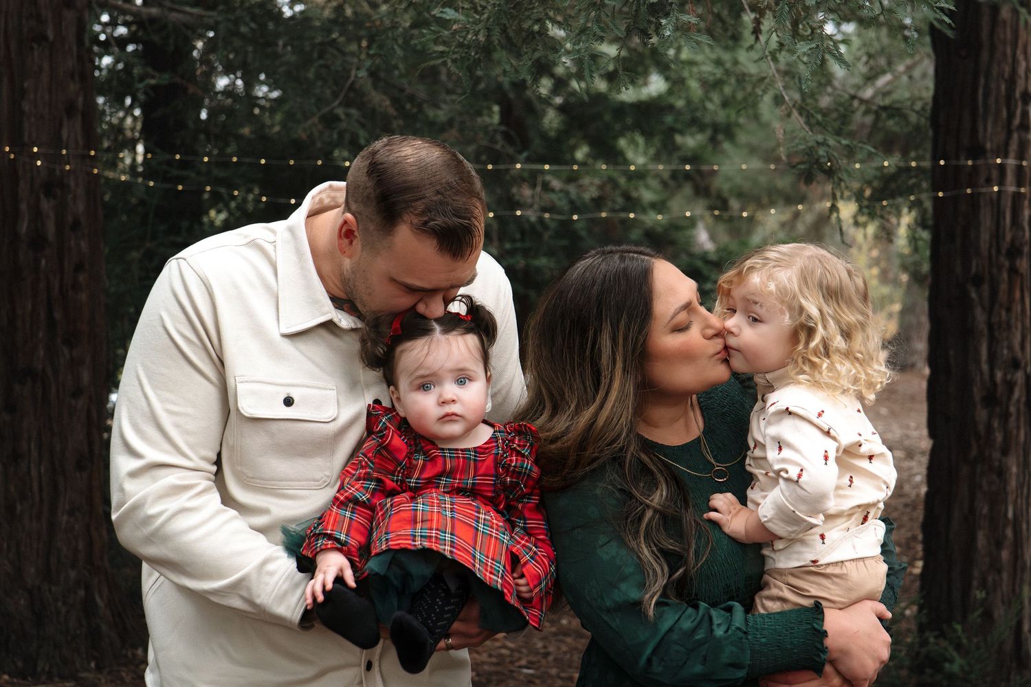 Family cuddles together in forest setting wearing coordinated winter outfits in Roseville, CA