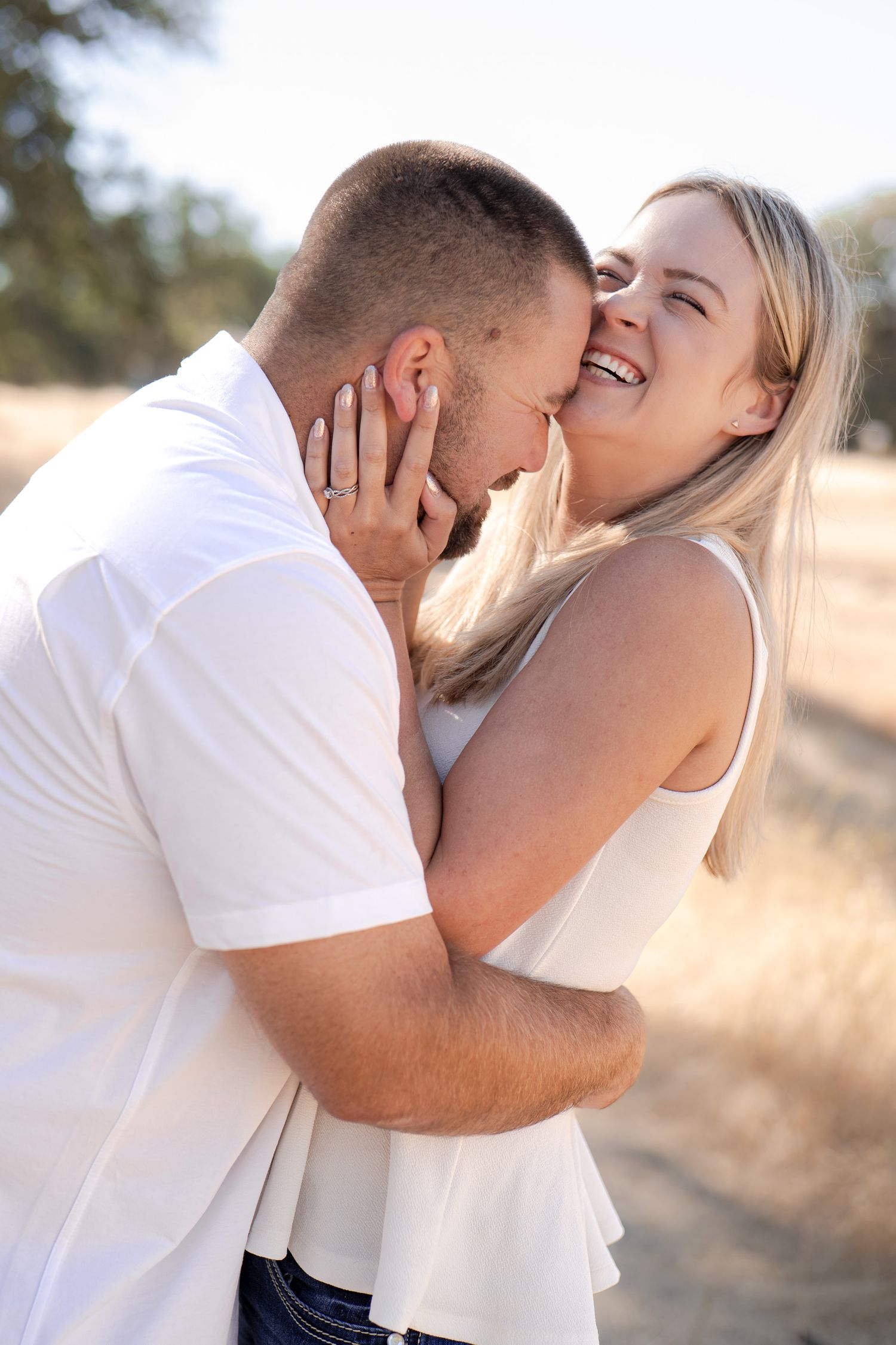 Affectionate couple sharing intimate moments in white clothing outdoors.