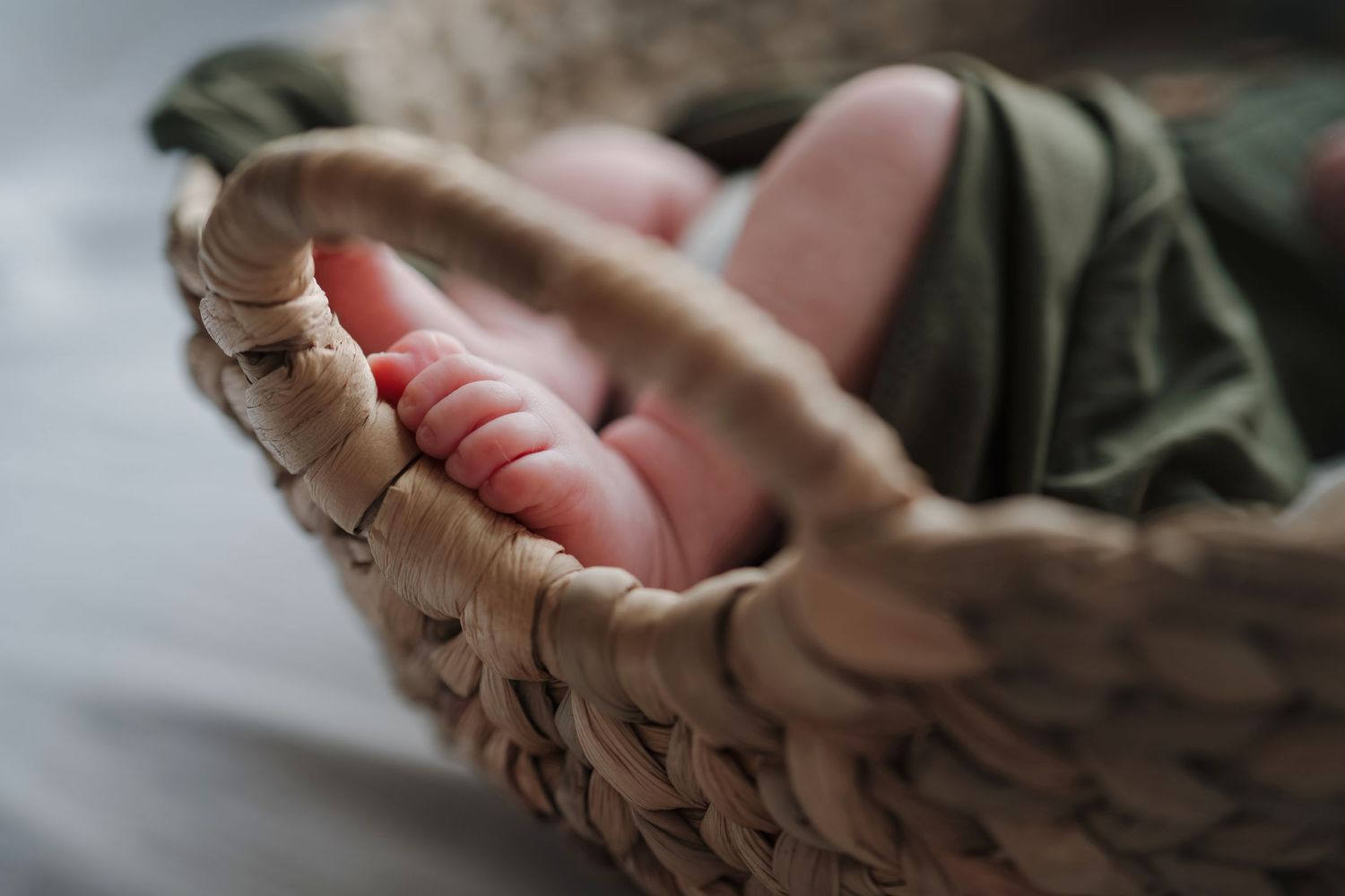 Close-up of hands weaving a brown wicker basket against a blurred background.