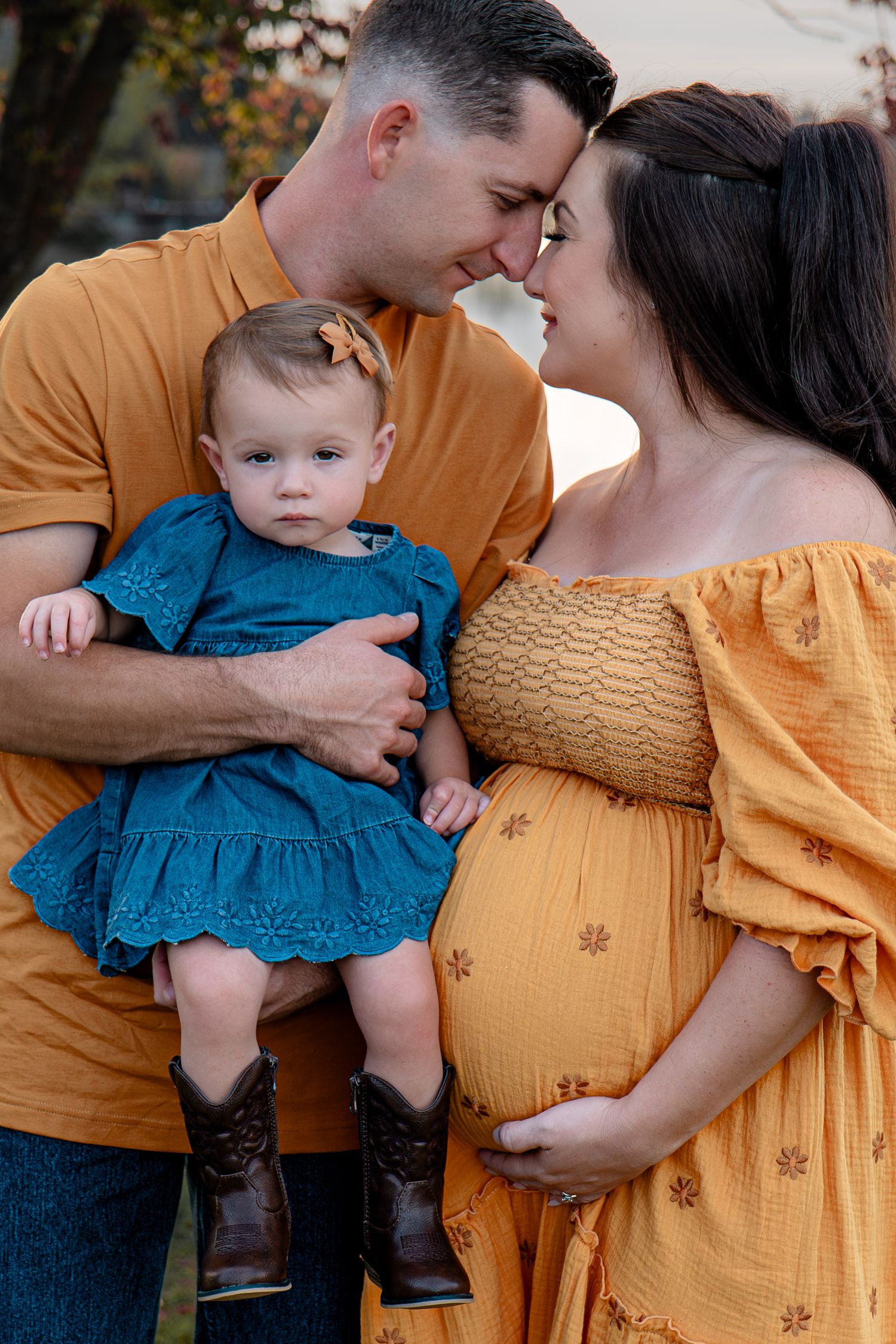 Family maternity photo session with couple in yellow and blue outfits by a lake in Roseville, CA