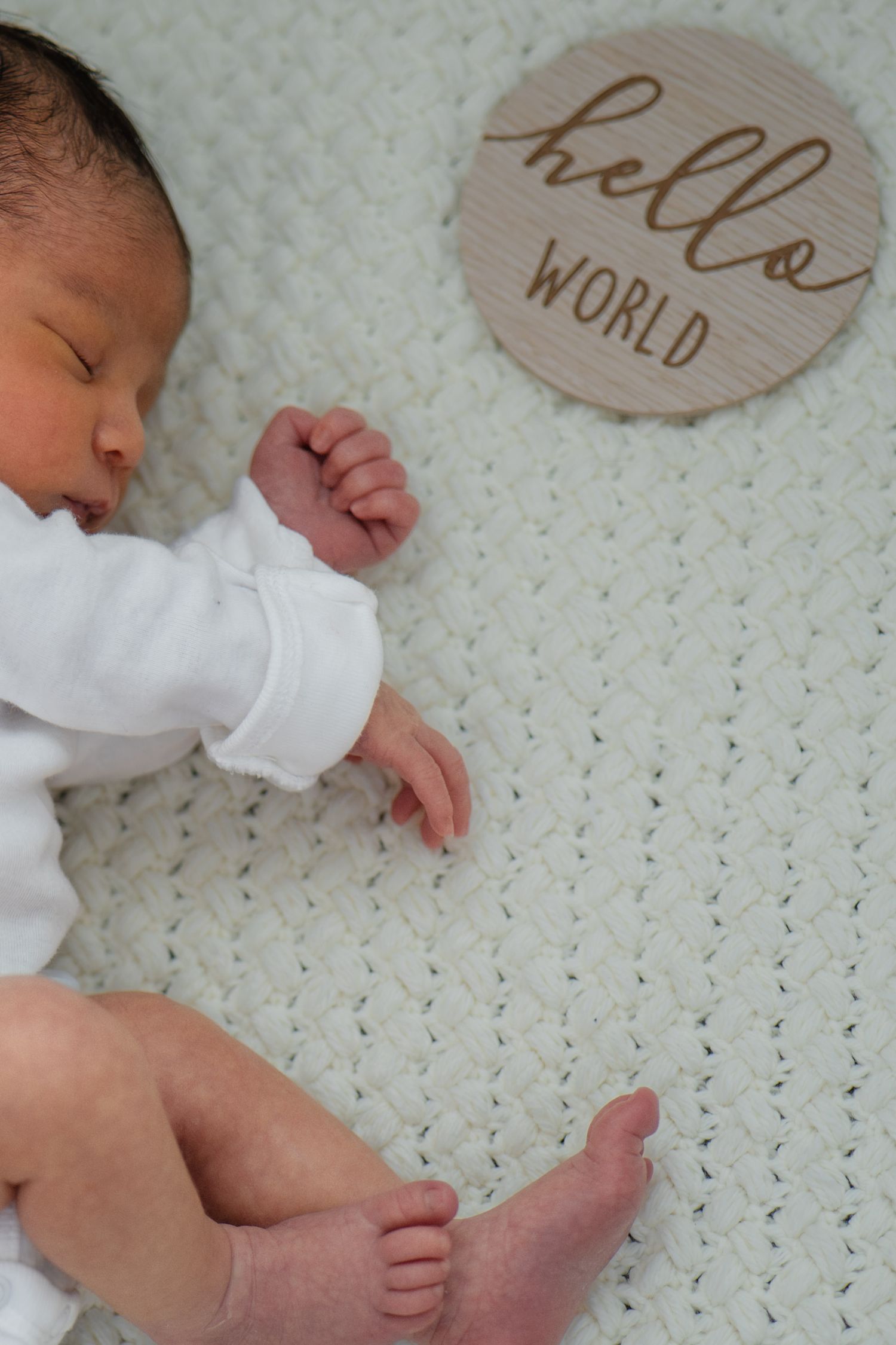 Close-up of baby feet and wooden milestone markers on white knit blanket in Roseville, CA