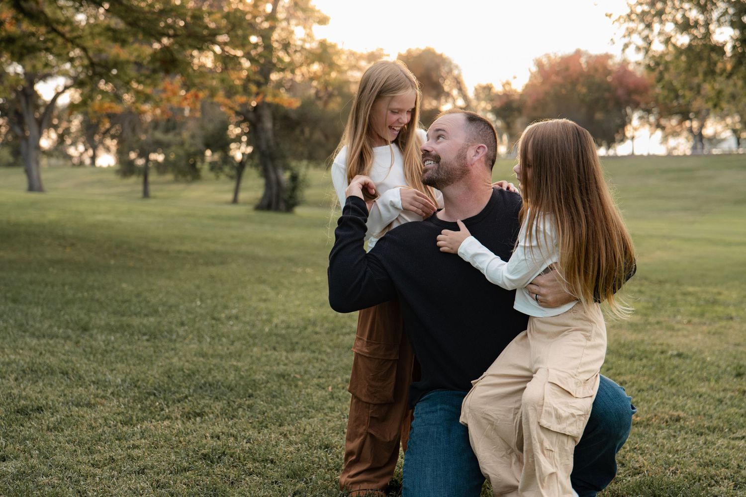 Candid family moments captured at sunset in a park with warm autumn lighting in Roseville, CA