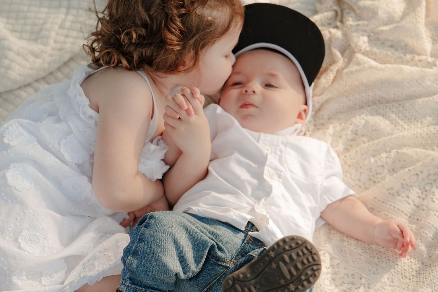 Sweet candid moments of parent and baby resting together on a white blanket.