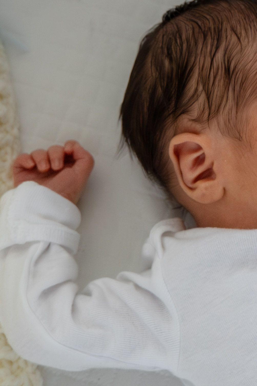 Sleeping newborn in white onesie captured in profile view in Roseville, CA