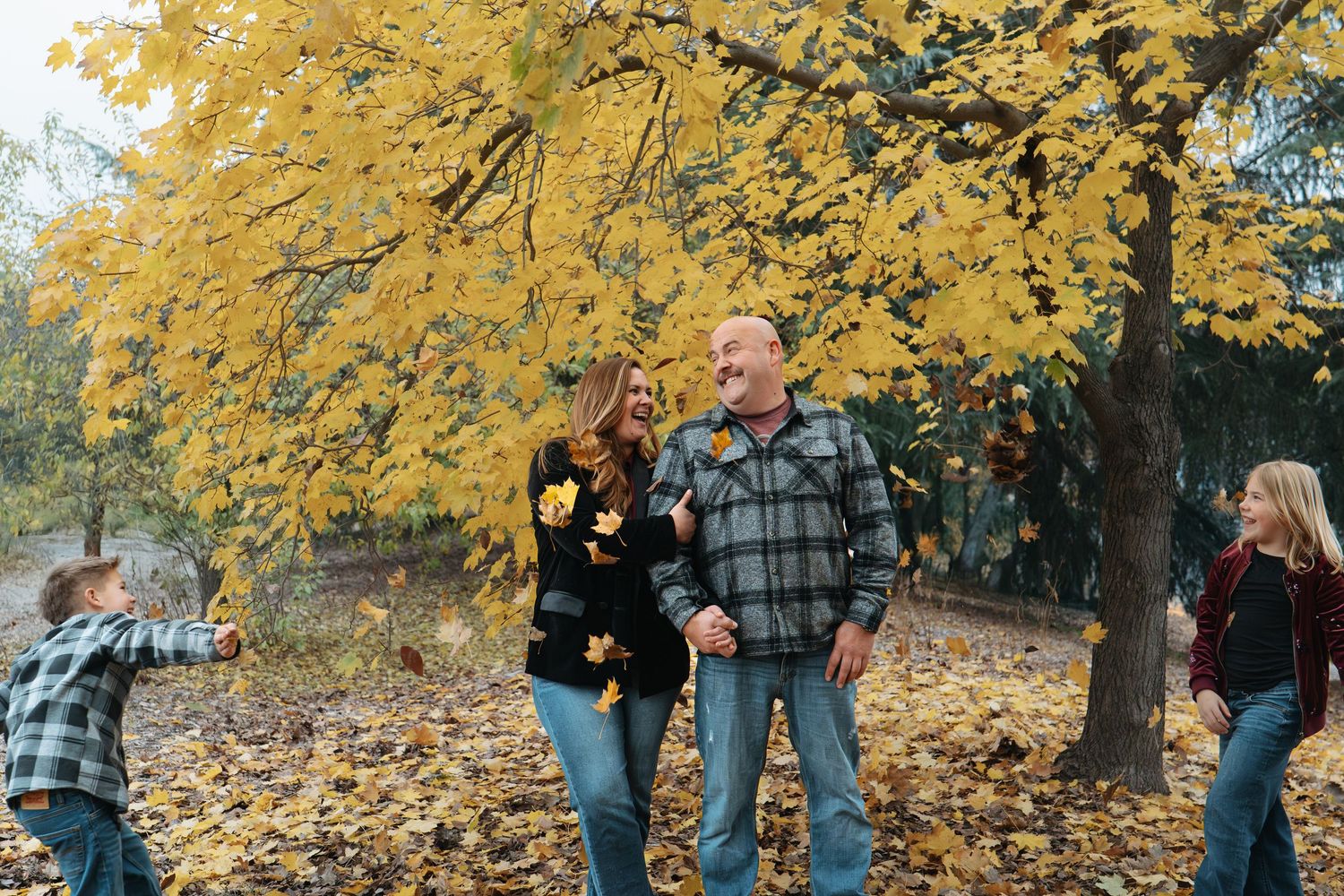 Family gathering under golden autumn trees with string lights creating a warm atmosphere in Roseville, CA