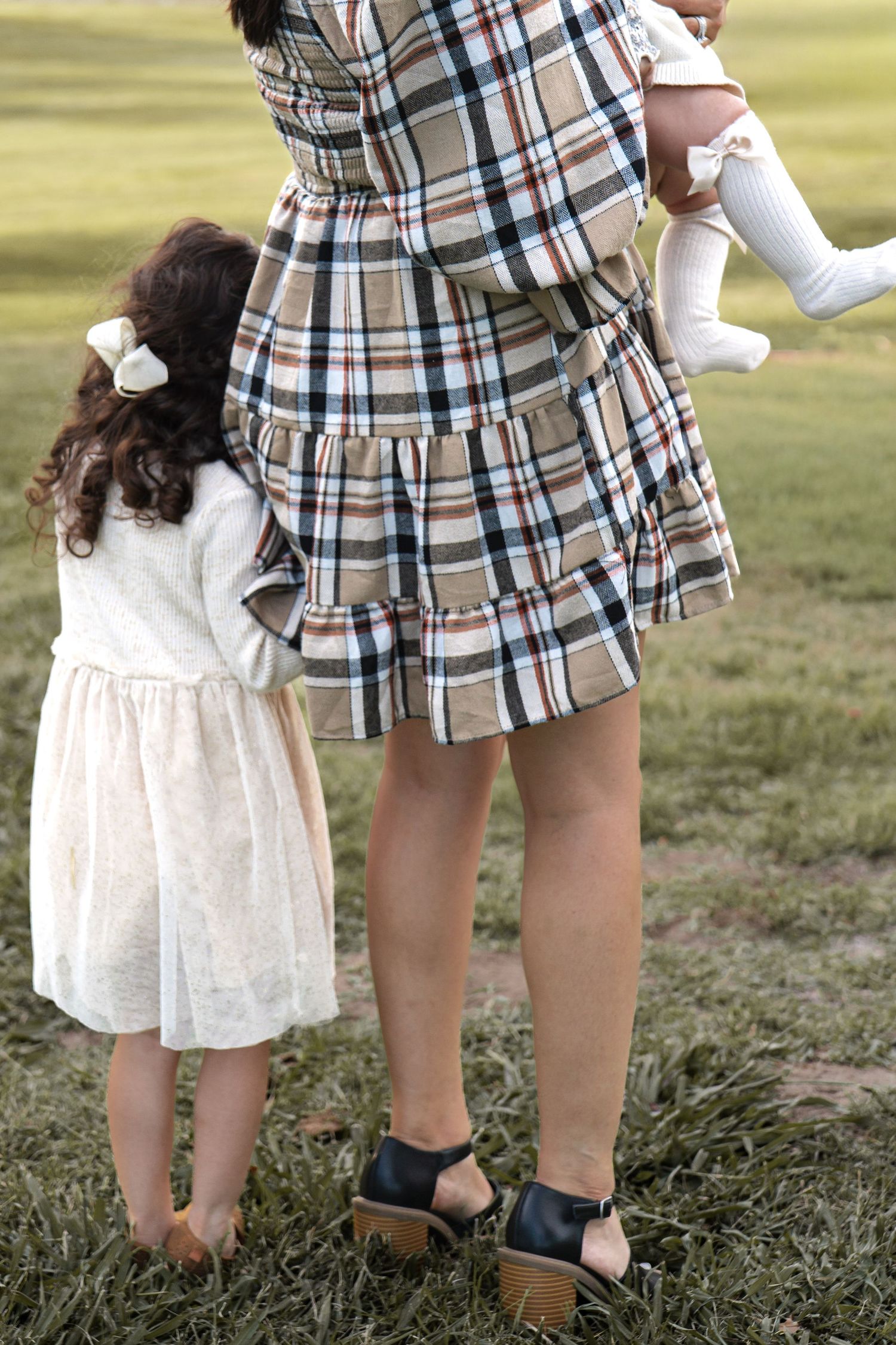 Close-up view of plaid dress and white lace dress details during outdoor family photoshoot in Roseville, CA