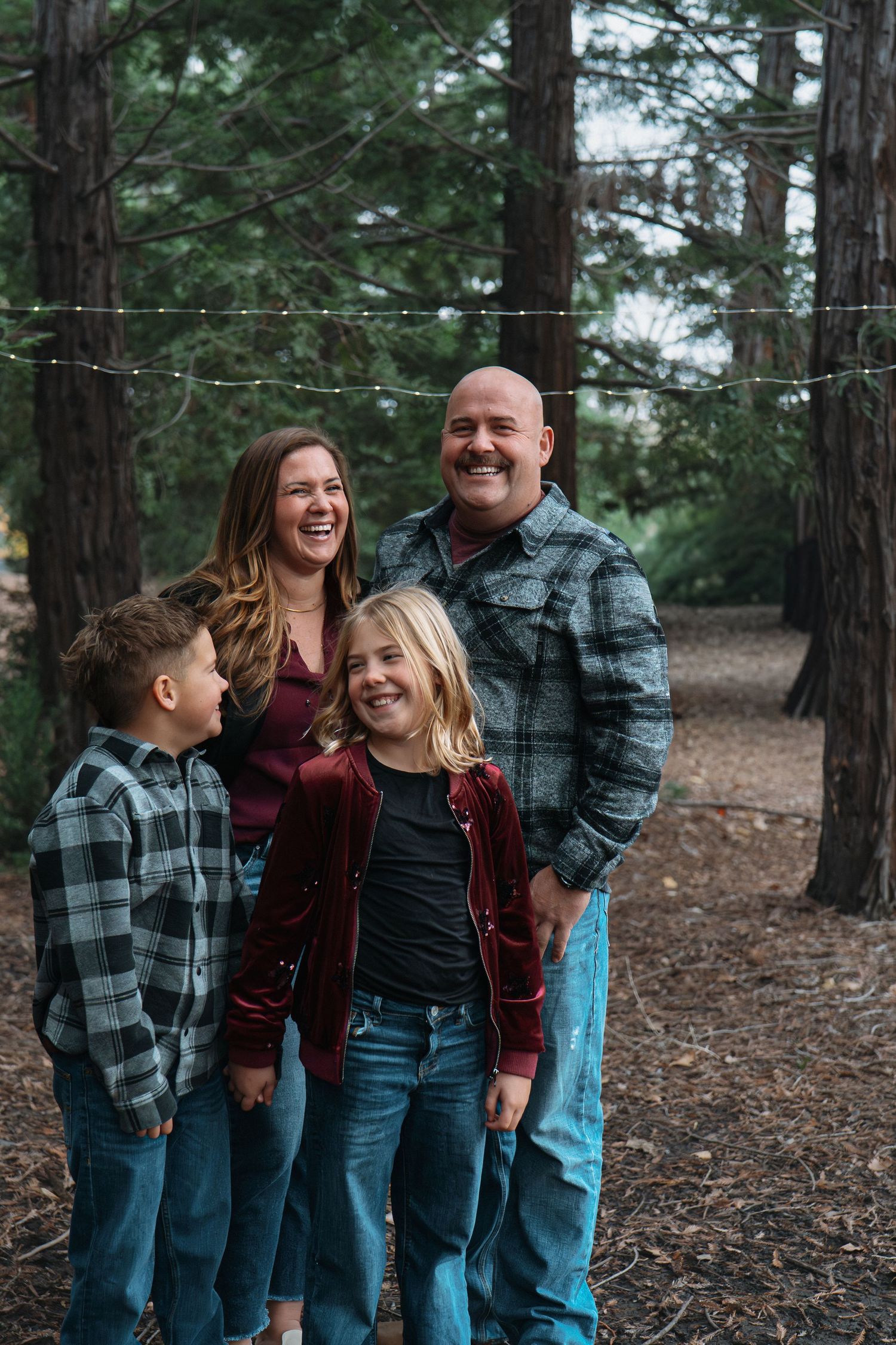 Family laughing together in casual attire among pine trees in Roseville, CA