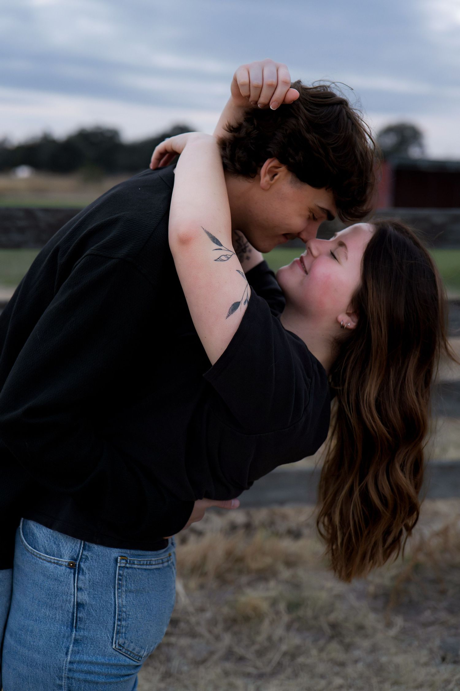 Couple in casual wear sharing romantic poses against a natural backdrop in Roseville, CA
