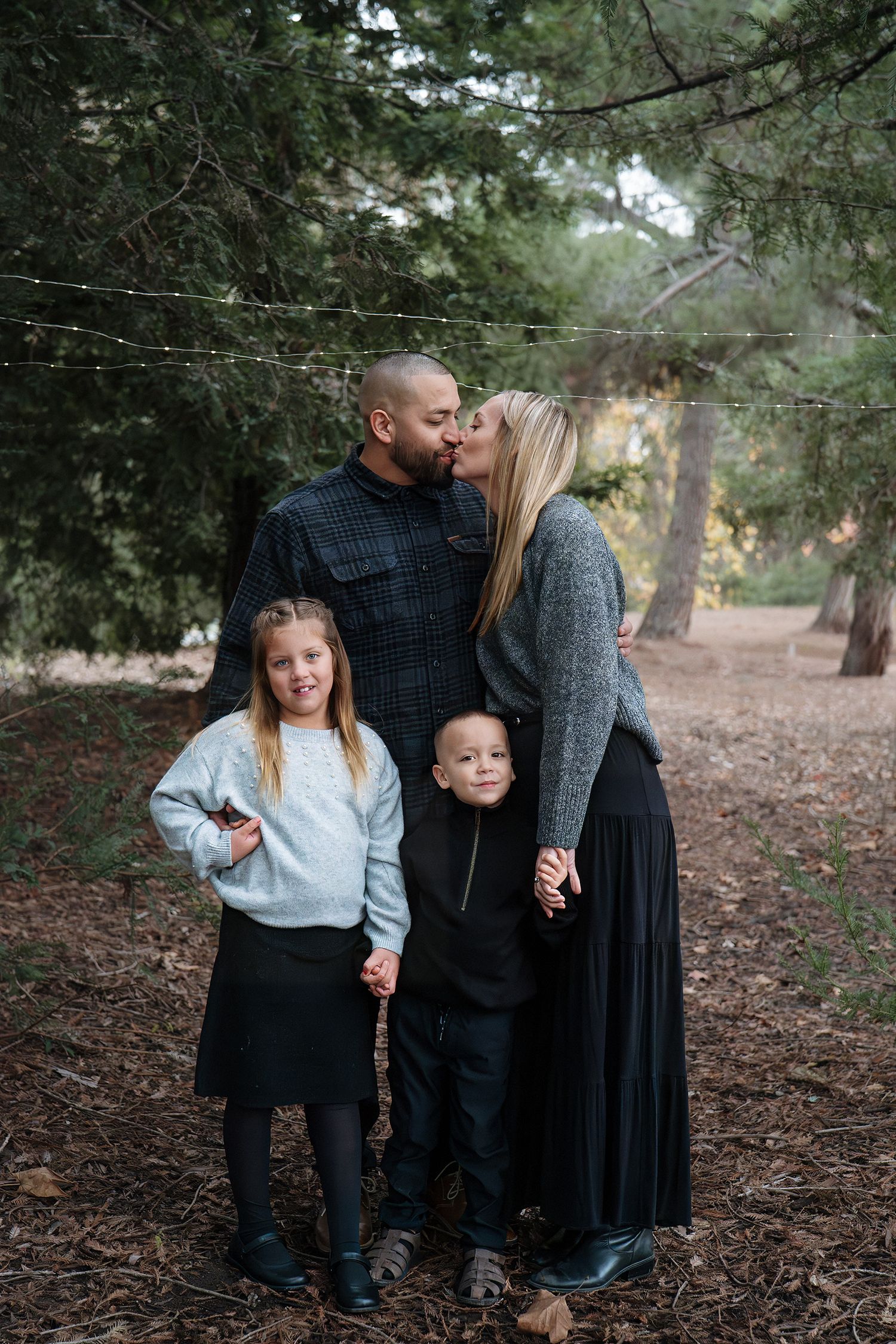 Family of four sharing intimate moments in a wooded forest setting in Roseville, CA